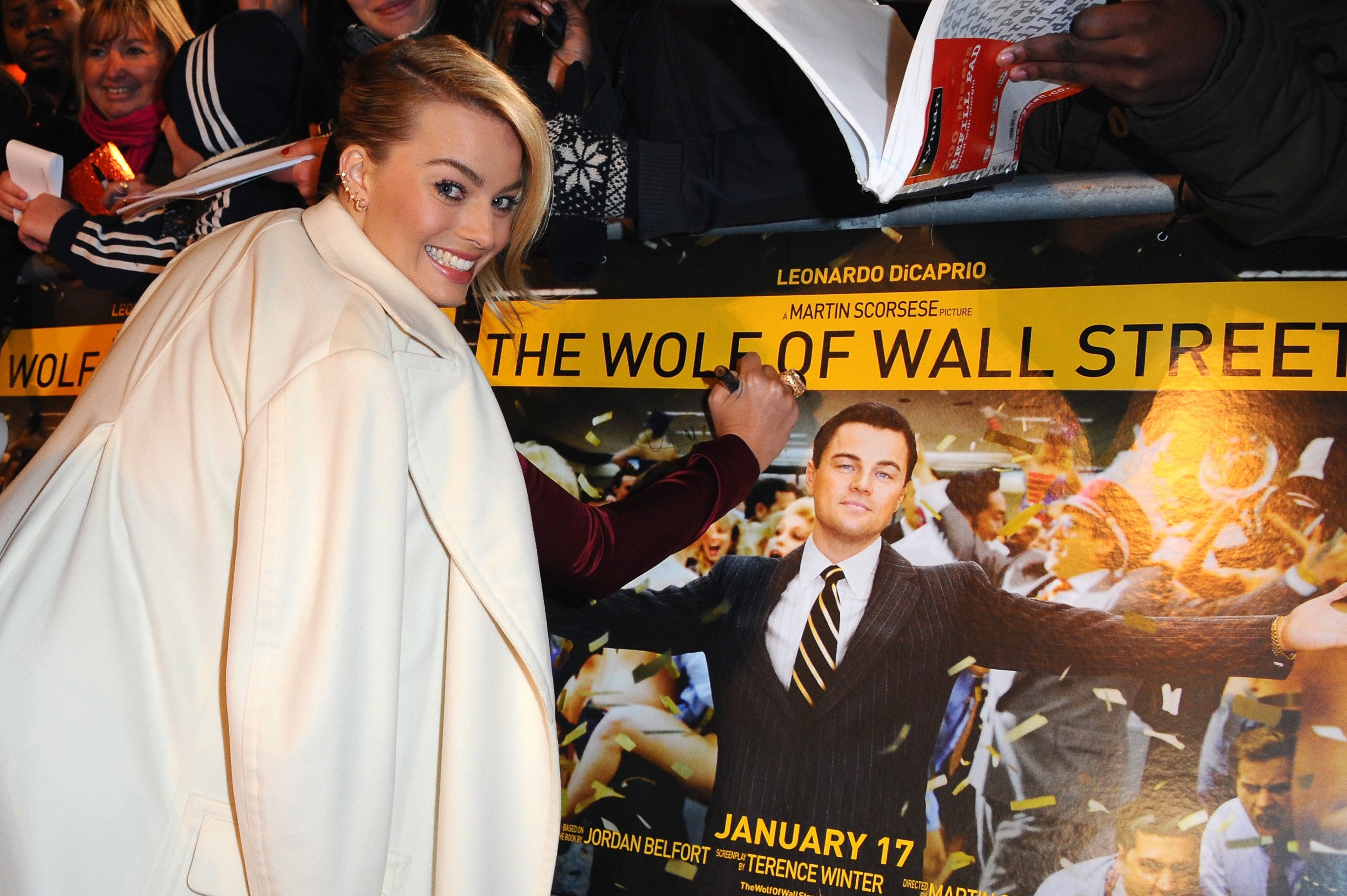 Actress Margot Robbie signs her name on a film poster as she attends the UK Premiere of The Wolf of Wall Street at London's Leicester Square on January 9, 2014 in London, England.