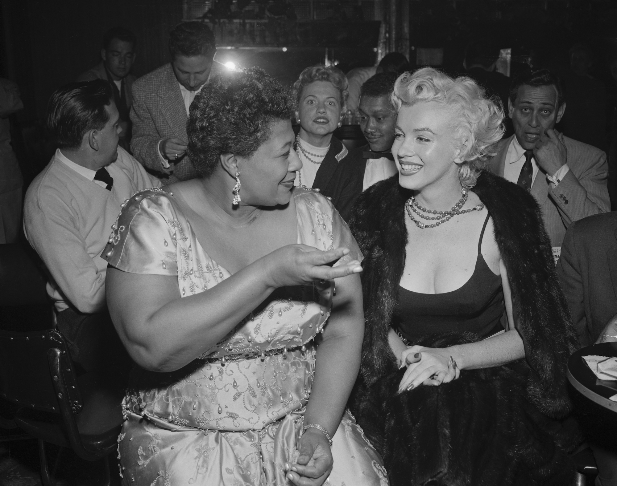 (L-R) Ella Fitzgerald and Marilyn Monroe turned to each other, laughing
