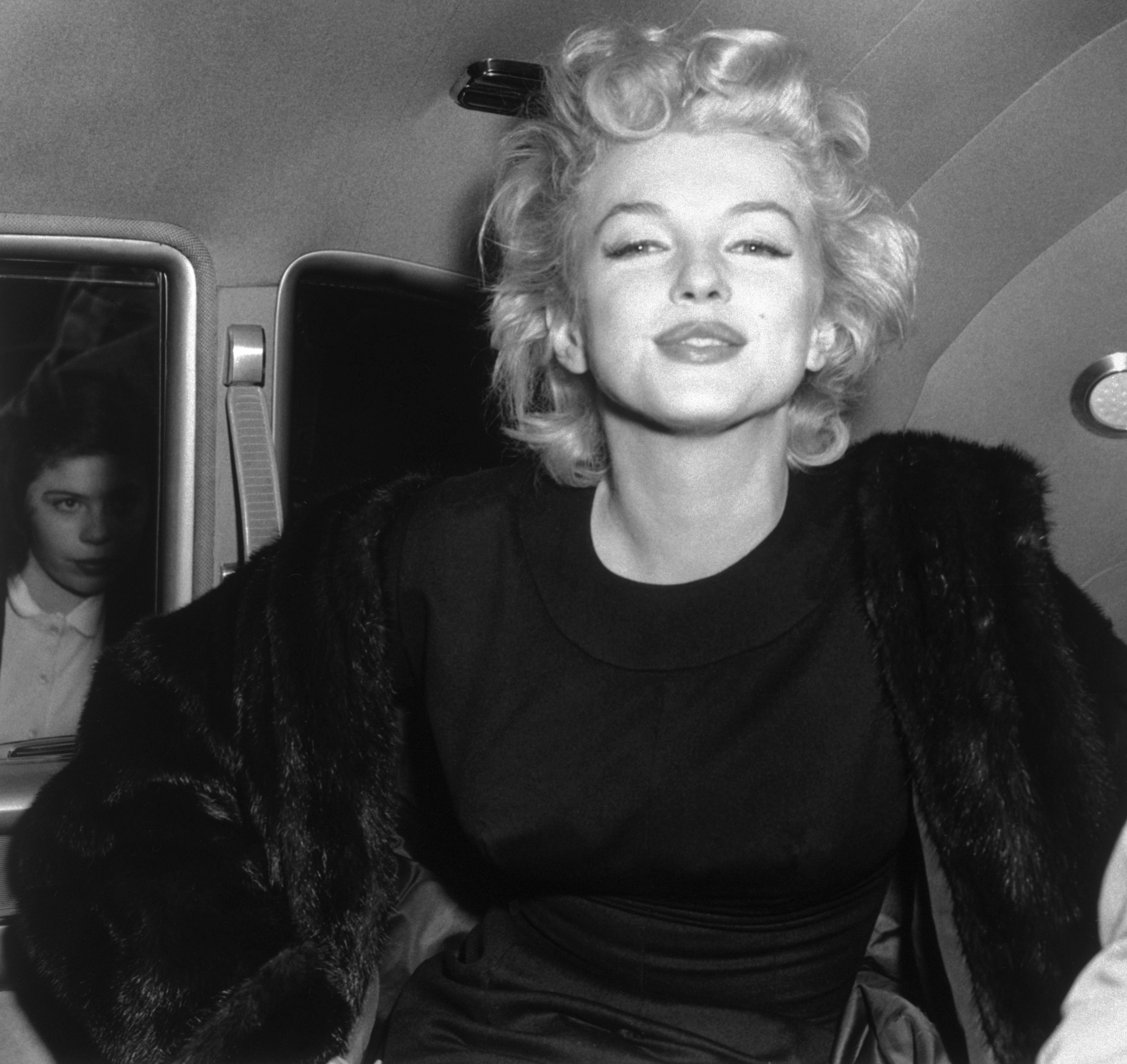 Marilyn Monroe smiles for a photo in the back of a car