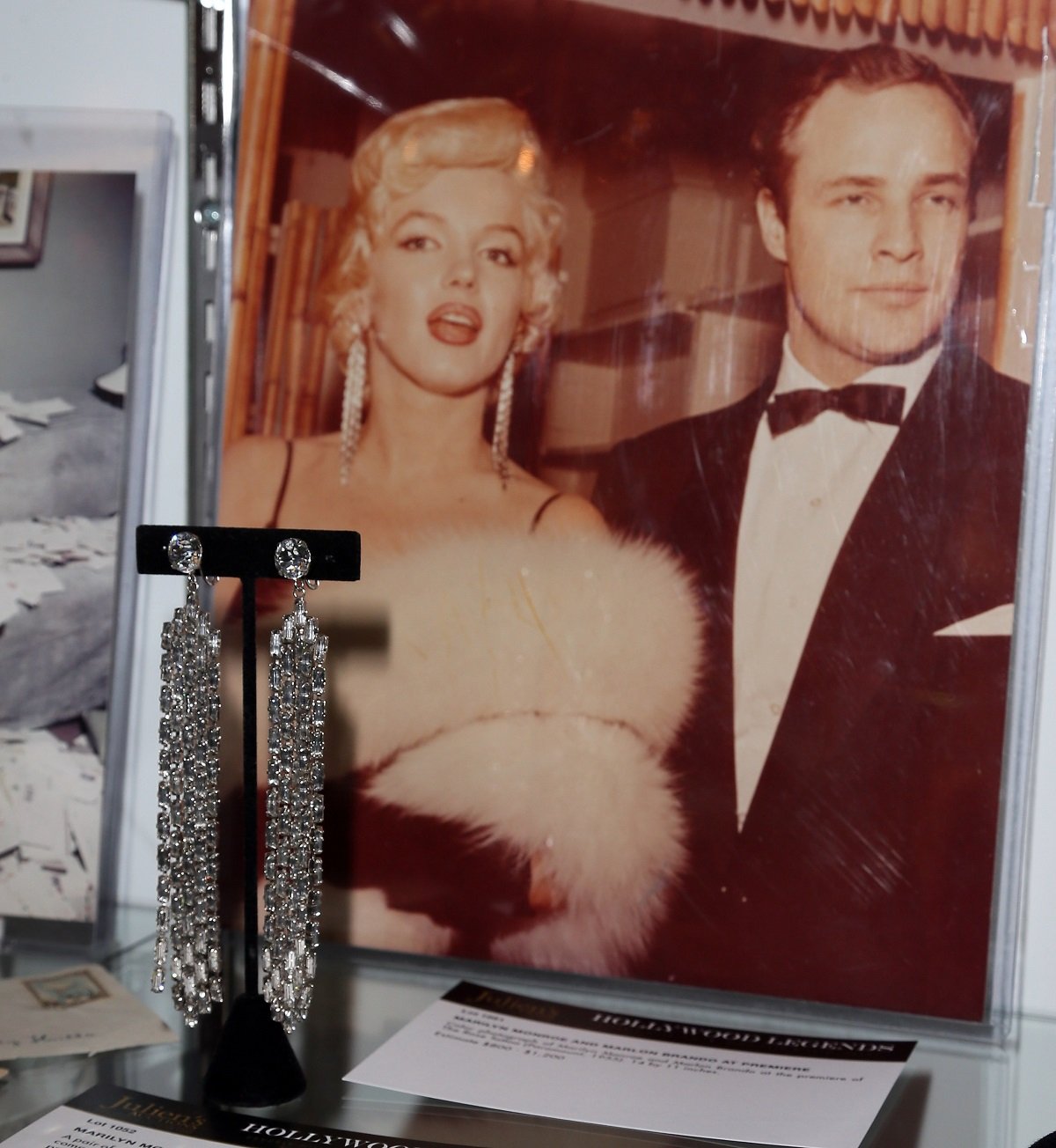 Marilyn Monroe's earrings in front of a photo of Monroe with Marlon Brando at a 2014 auction