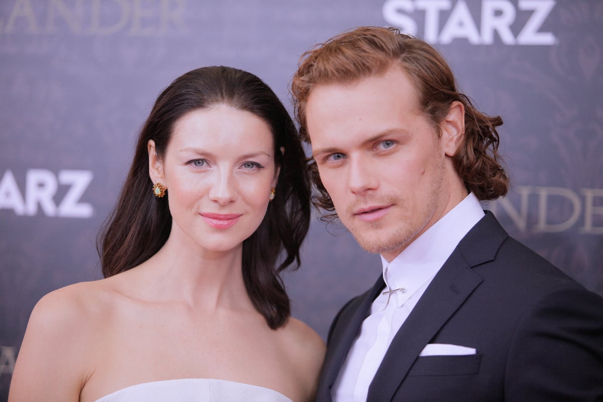 Outlander Caitriona Balfe and Sam Heughan pose for a photo at an awards show.