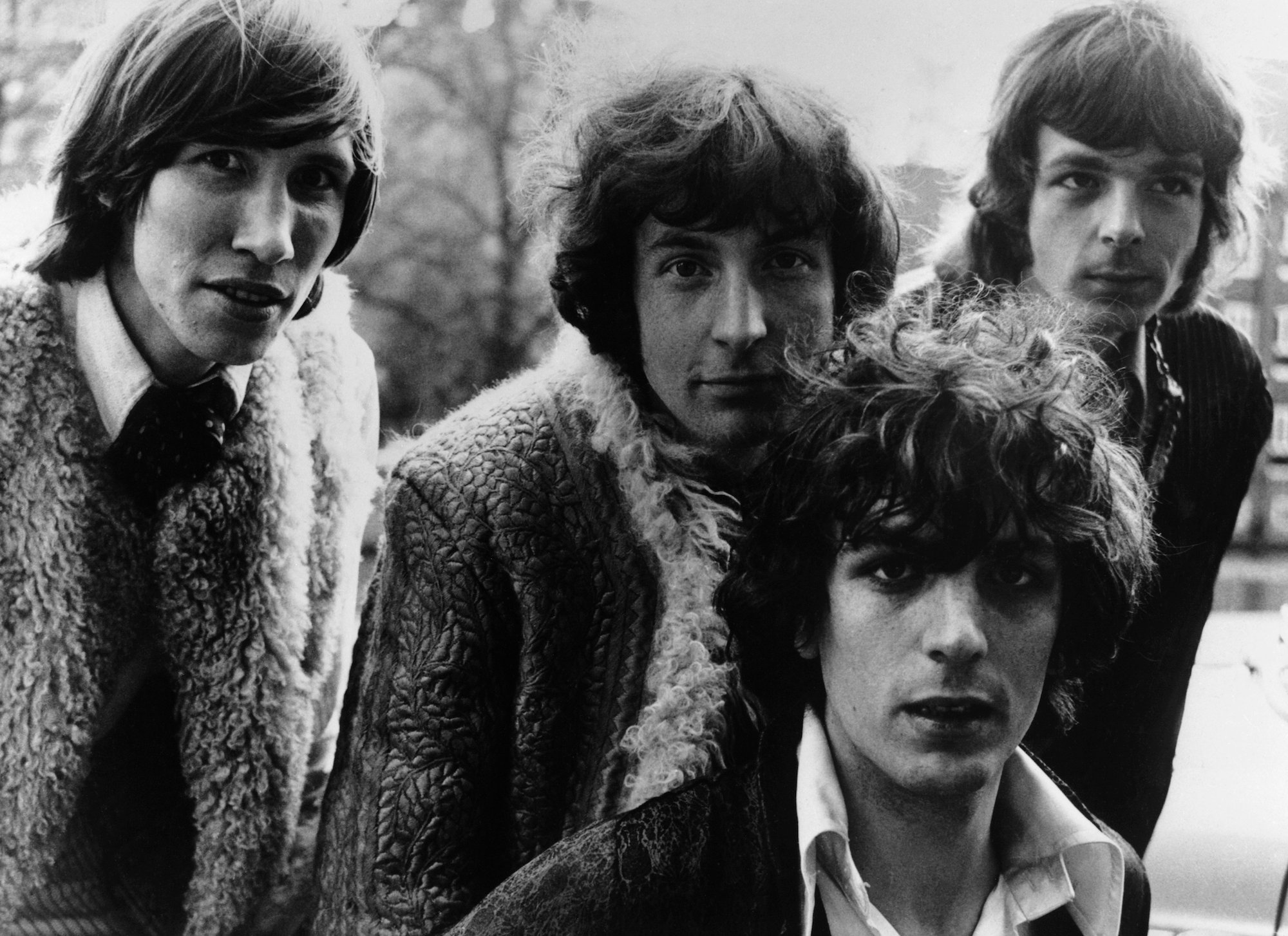(L-R) Roger Waters, Nick Mason, Syd Barrett and Richard Wright smiling slightly, in black and white