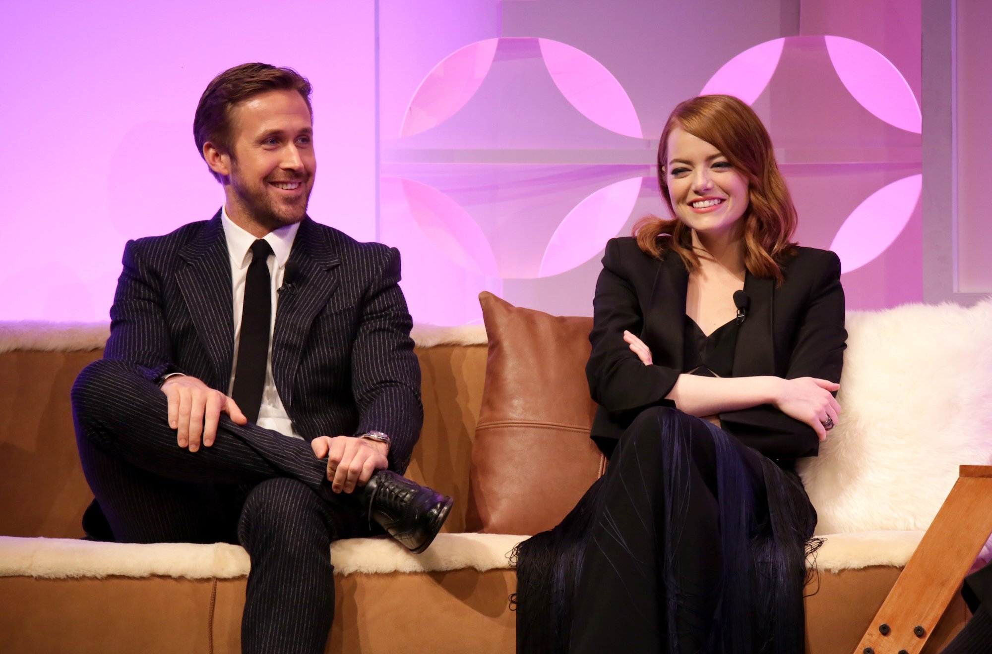 (L-R) Ryan Gosling and Emma Stone smiling, sitting on a couch