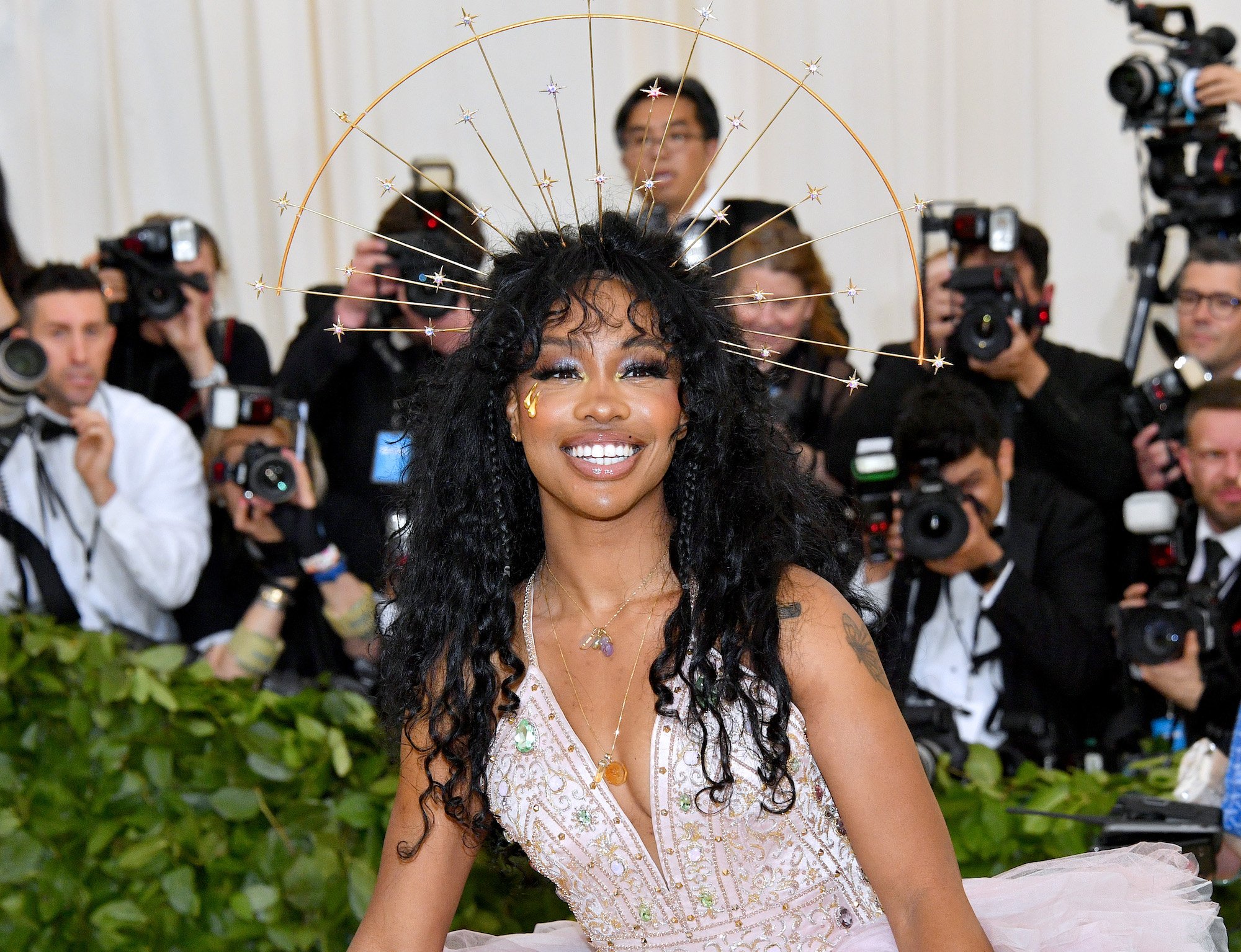 SZA smiling in front of a crowd of photographers
