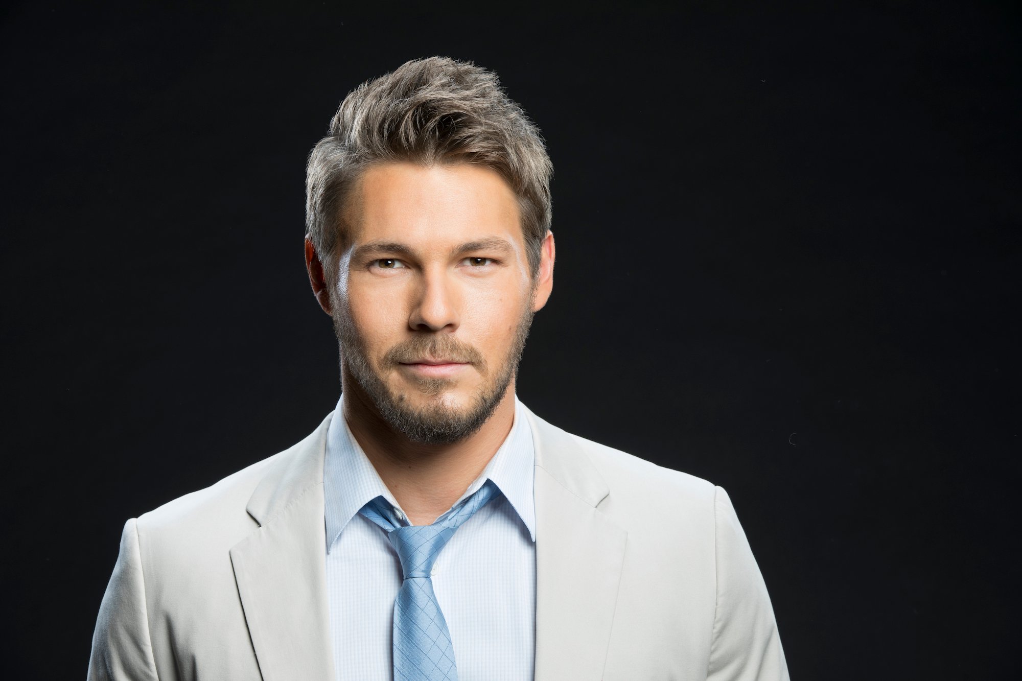 Scott Clifton slightly smiling in front of a black background