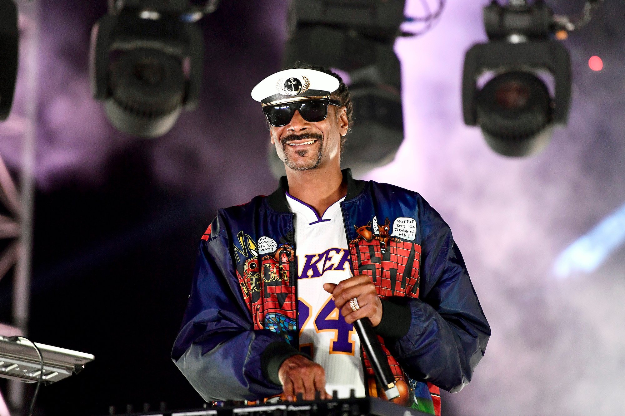 Snoop Dogg smiling at a soundboard, on stage