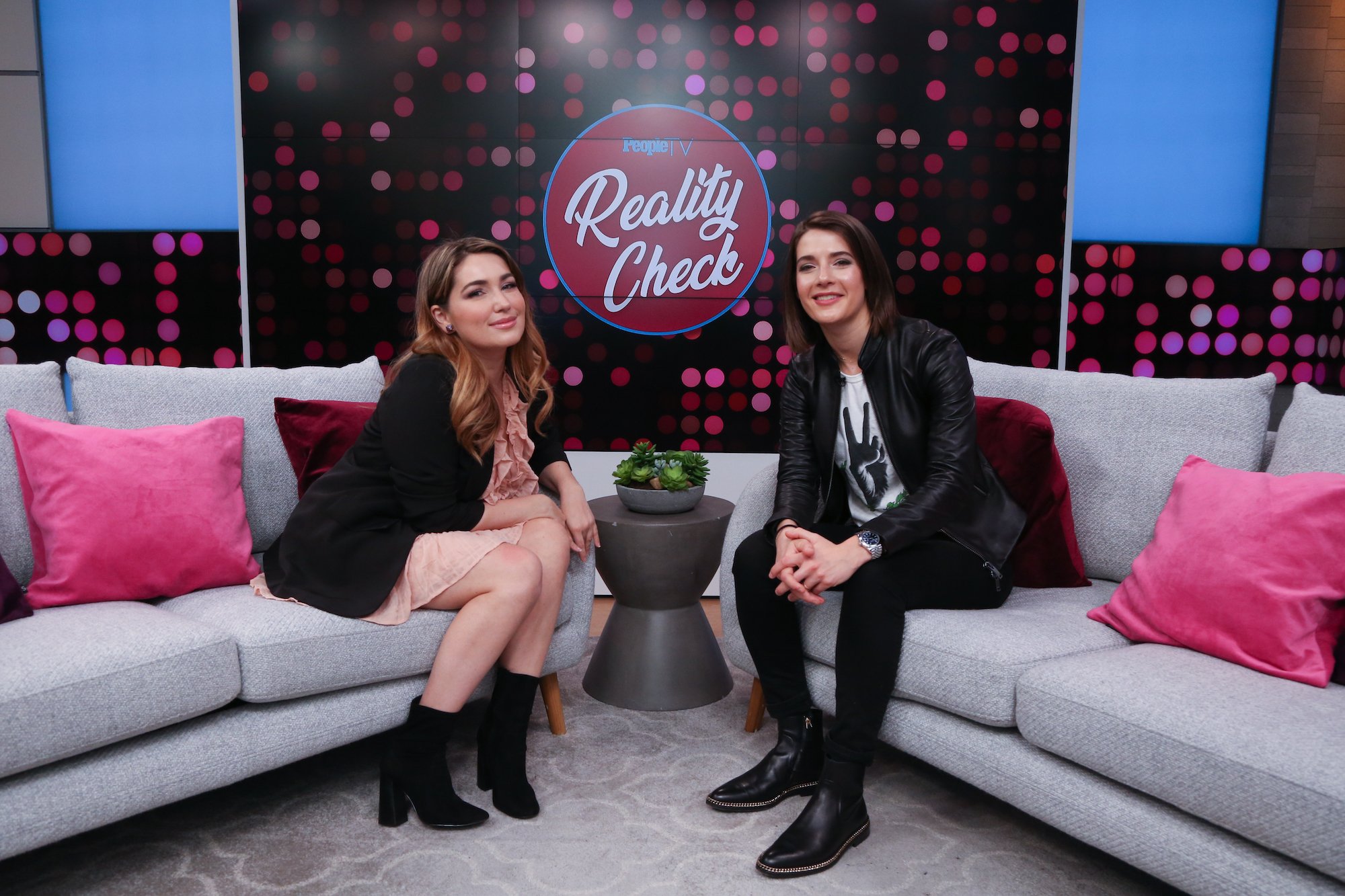 (L-R) Stephanie Matto and Daryn Carp sitting on separate couches, smiling at the camera