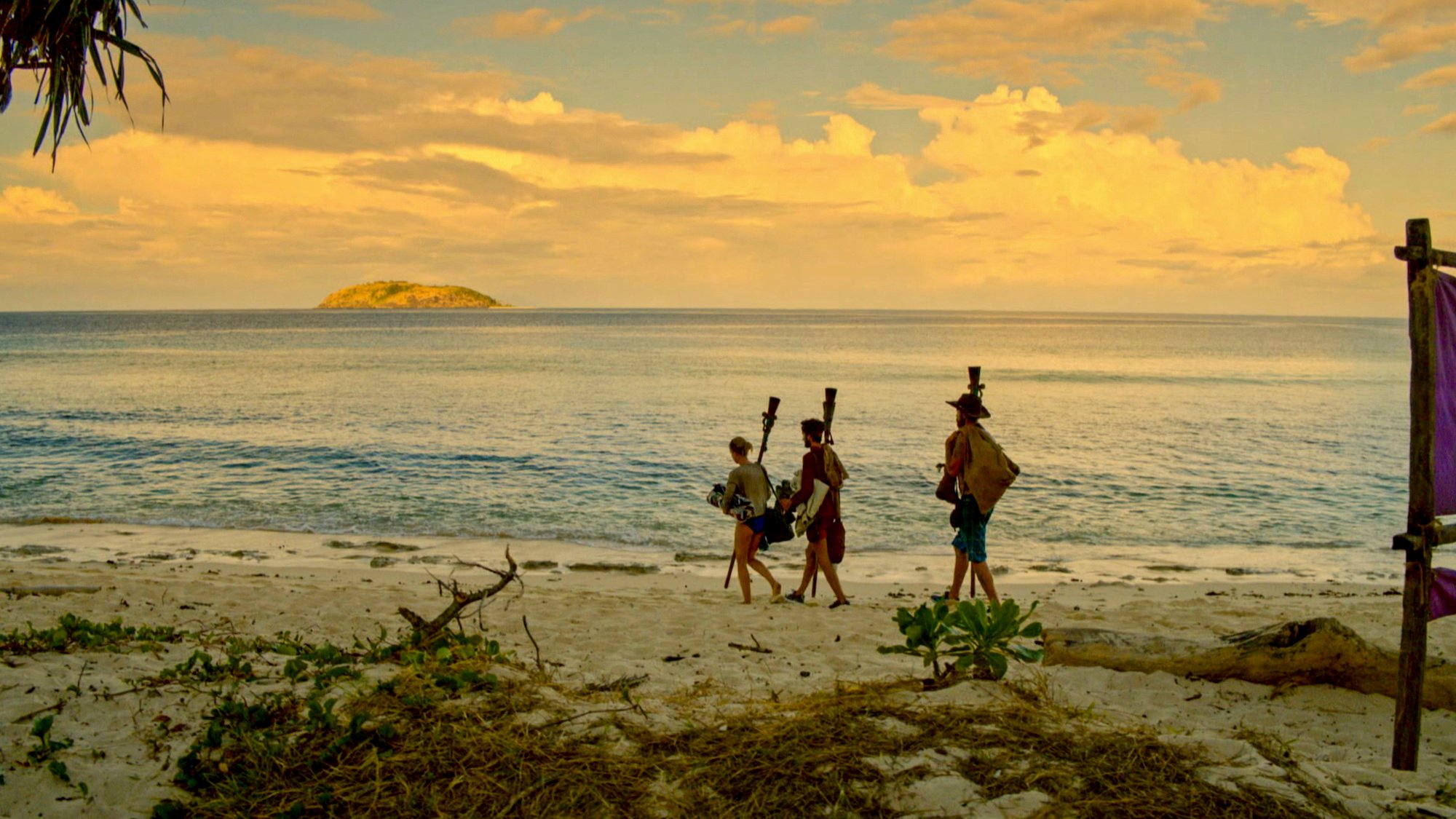 Survivor castaways on a beach, carrying torches