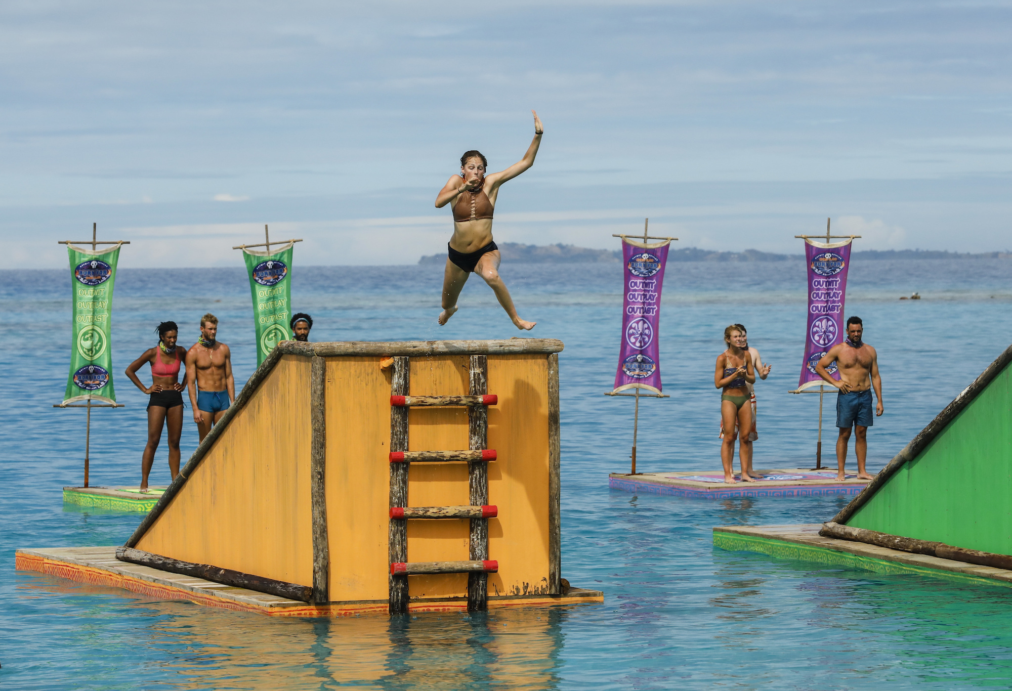Survivor contestants competing on the show, in the water, with one contestant jumping off a platform
