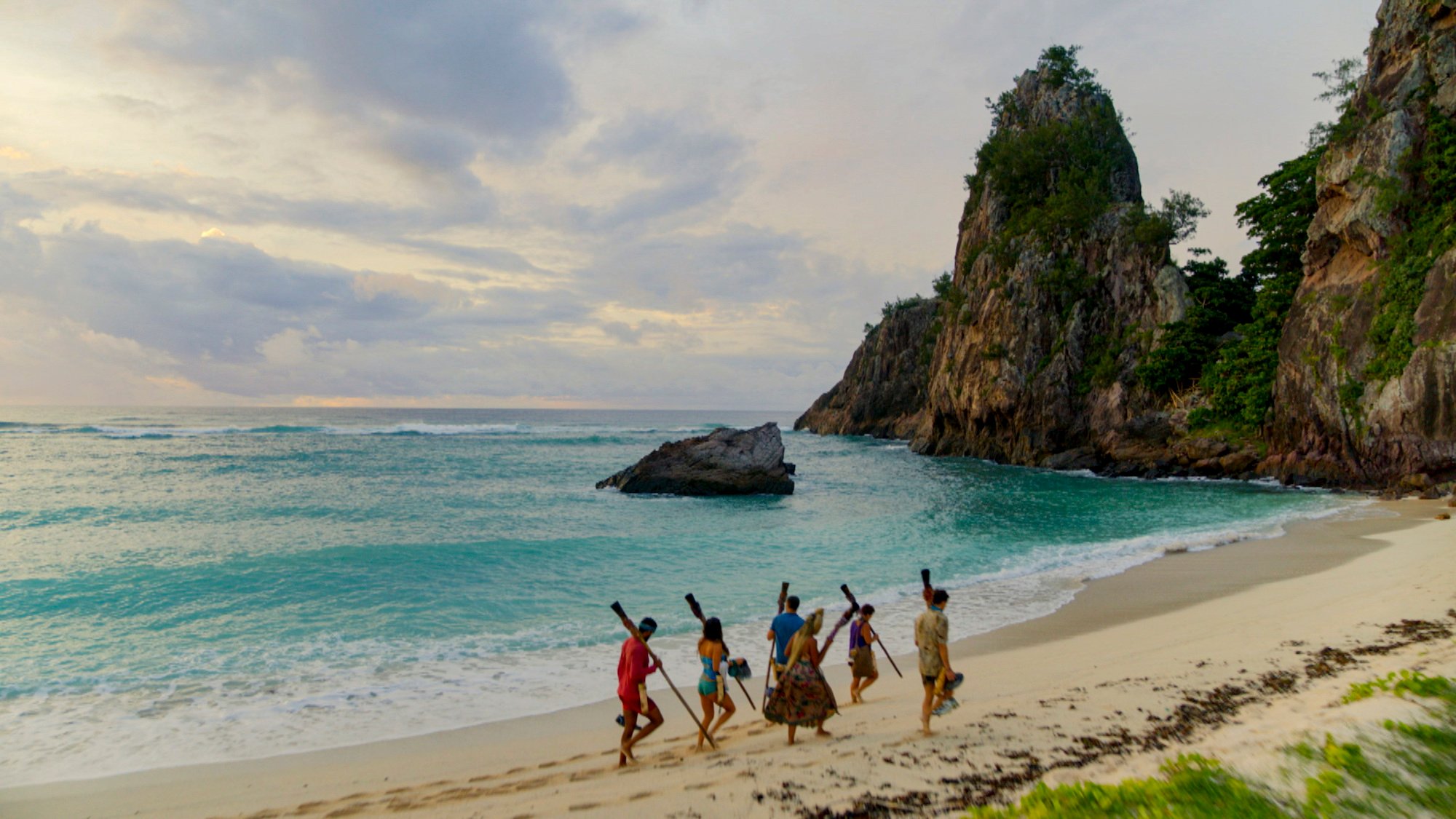 Survivor cast walking on a beach in front of the ocean