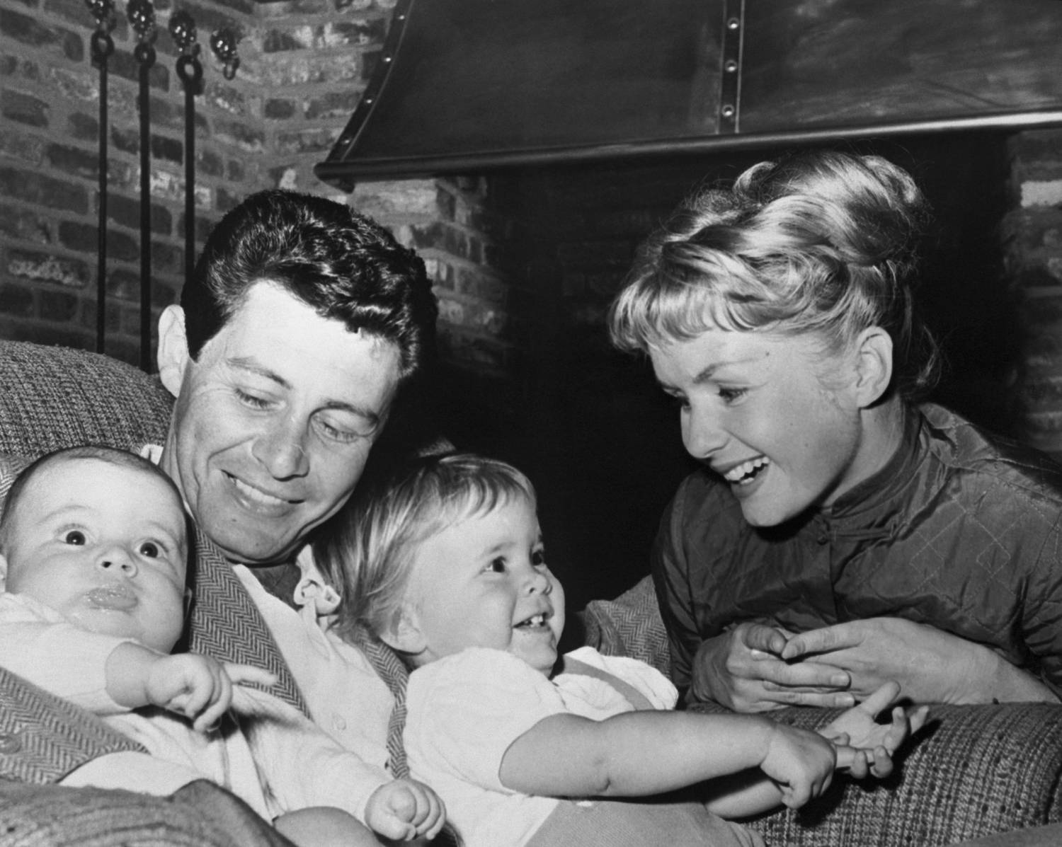 (Original Caption) Hollywood: A newcomer to the ranks of fatherhood, Eddie Fisher was named "Father of the Year in TV" by the National Father's Day Committee. Mrs. Fisher (Debbie Reynolds) and the children presented Fisher with a handsome photo wallet containing their pictures. Carrie Frances is 19 months and son Todd (L) is 4 months old.