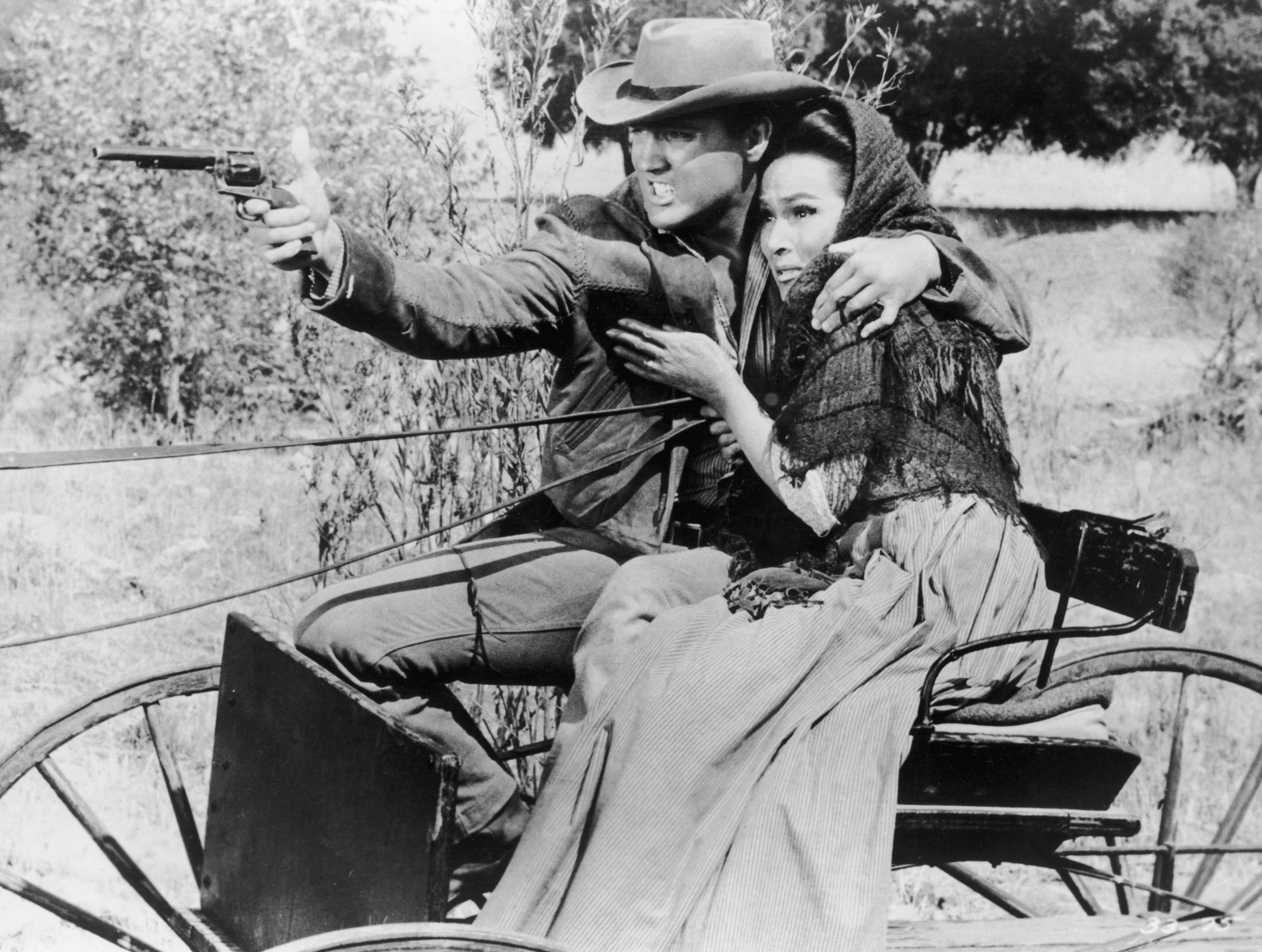 Elvis Presley holding a woman and a gun