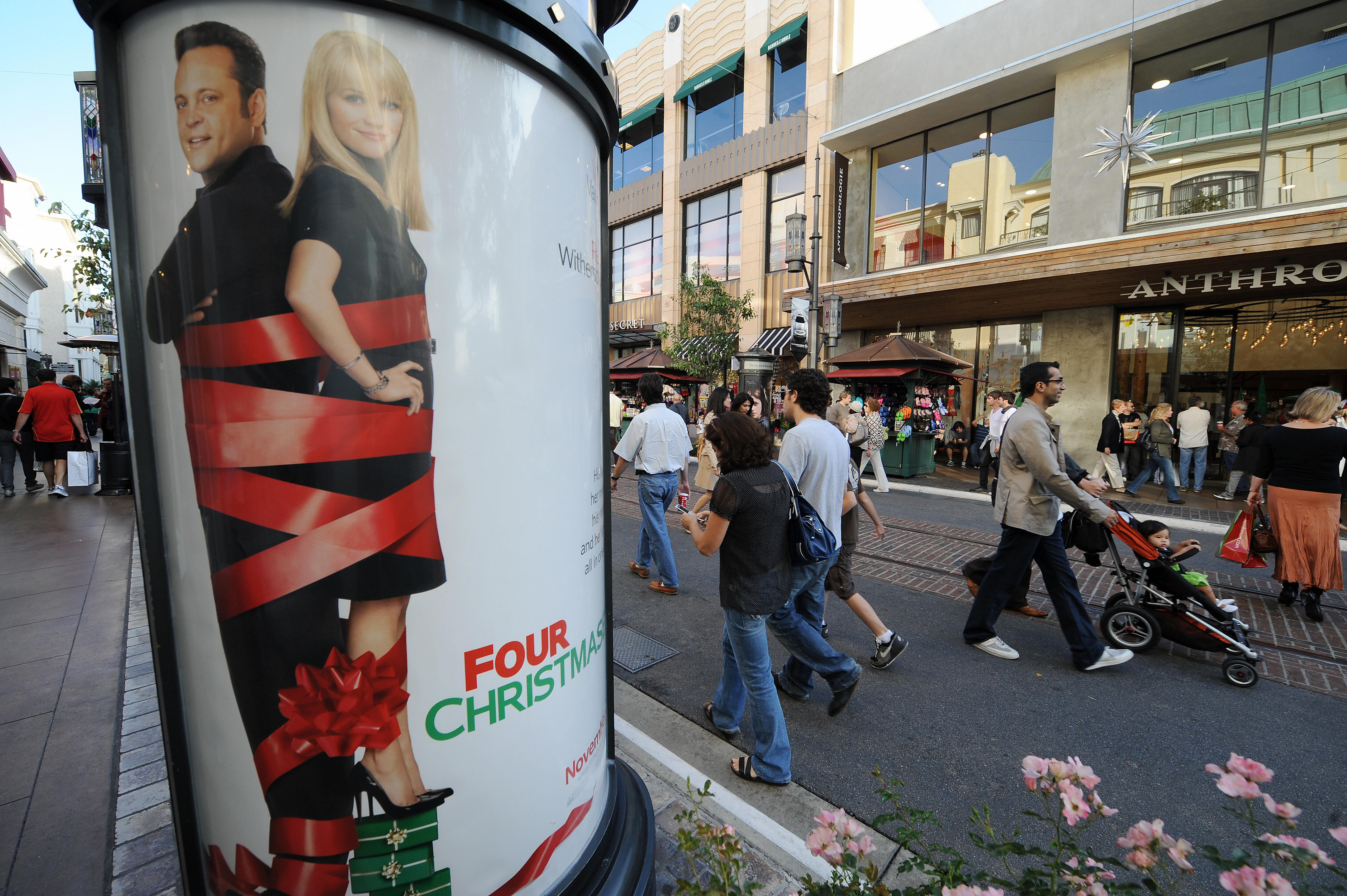 People walk past a poster advertising "F