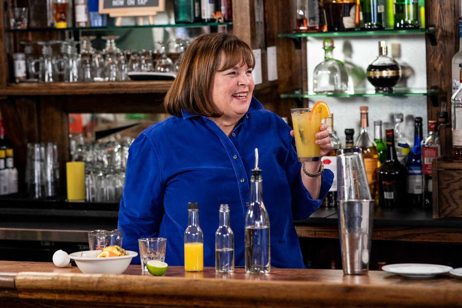 Ina Garten raises a cocktail while wearing a bright blue shirt on Late Night With Seth Meyers