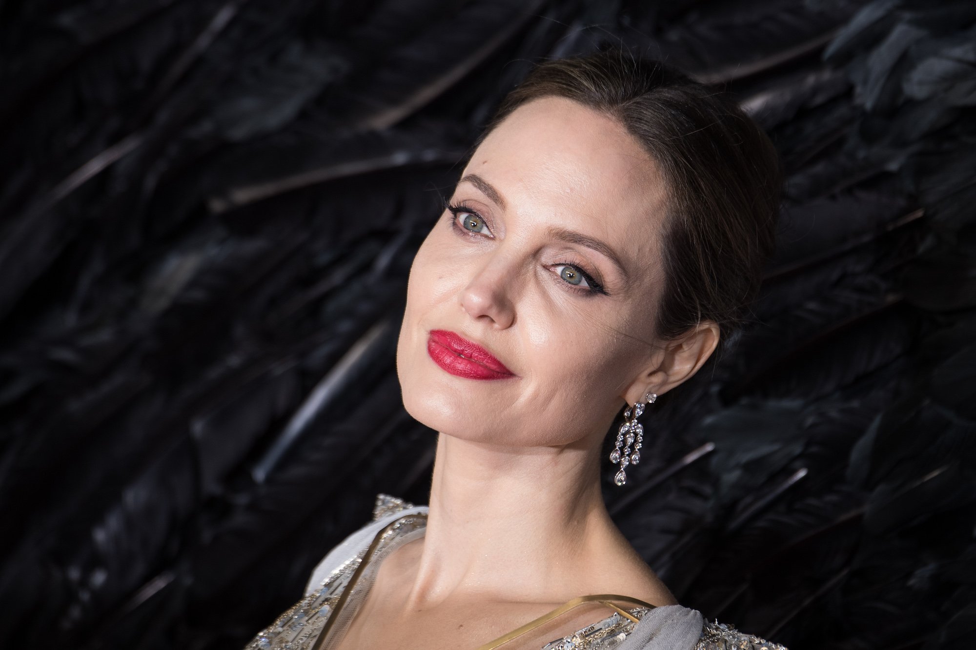 Angelina Jolie smiling in front of a black background