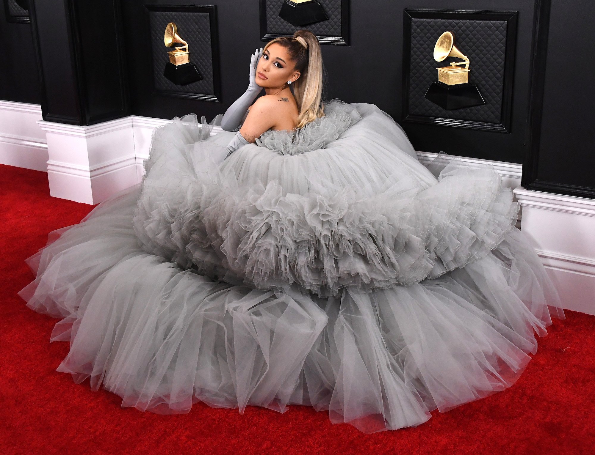 Ariana Grande crouched on the red carpet in a gray dress
