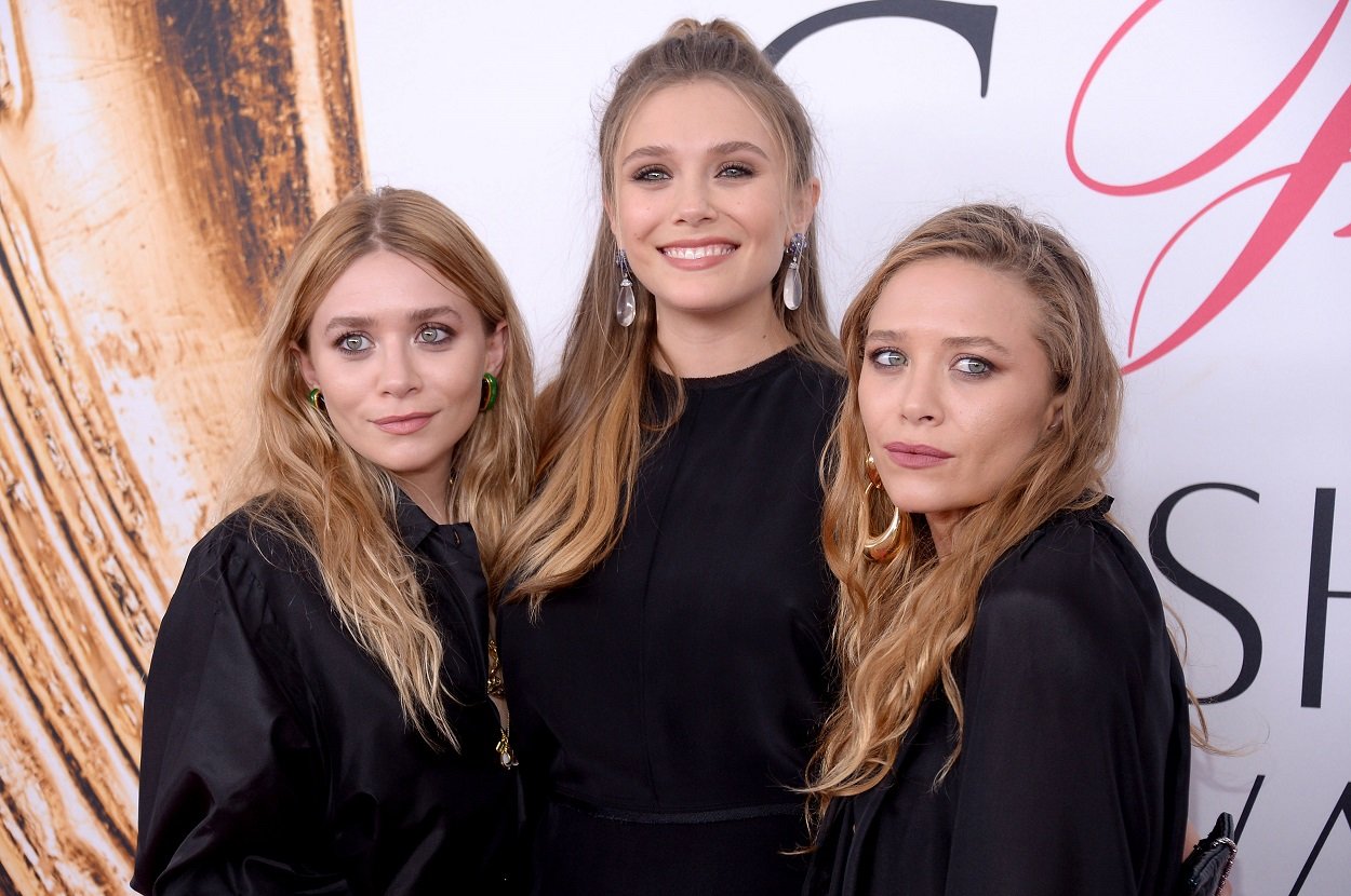 sisters Ashley Olsen, Elizabeth Olsen, and Mary-Kate Olsen all dressed in black posing together