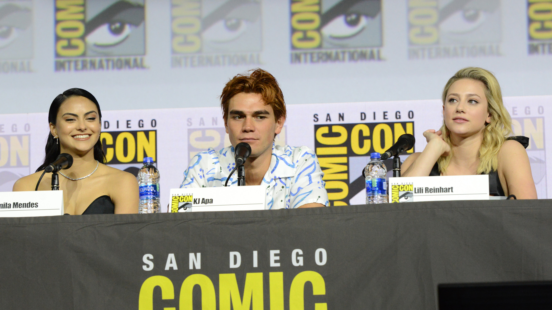 Camila Mendes (who plays Veronica Lodge), KJ Apa (who plays Archie Andrews), and Lili Reinhart (who plays Betty Cooper) speak at the "Riverdale" Special Video Presentation and Q&A during 2019 Comic-Con International at San Diego Convention Center on July 21, 2019 in San Diego, California.