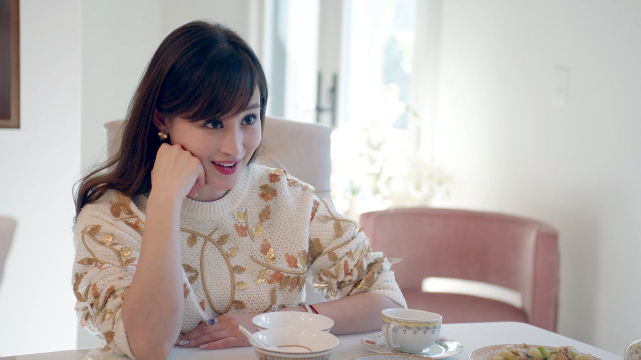 Cherie Chan smiling, leaning on her sand, seated at a table