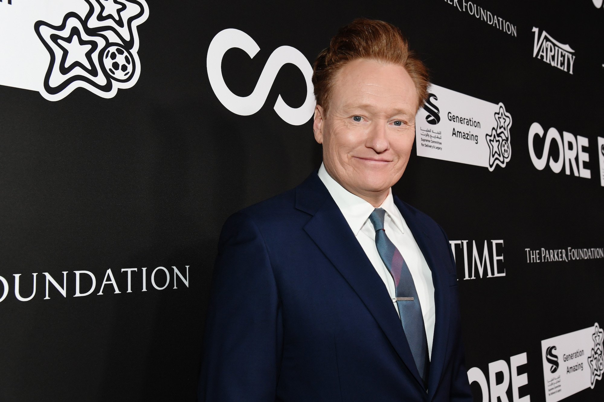 Conan O'Brien smiling in front of a black background