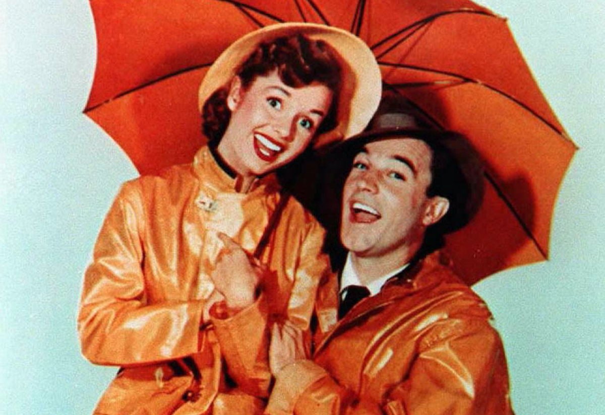 Debbie Reynolds (L) and Gene Kelly (R) in a promotional image for 'Singin' in the Rain' (1952) | FILE/AFP via Getty Images