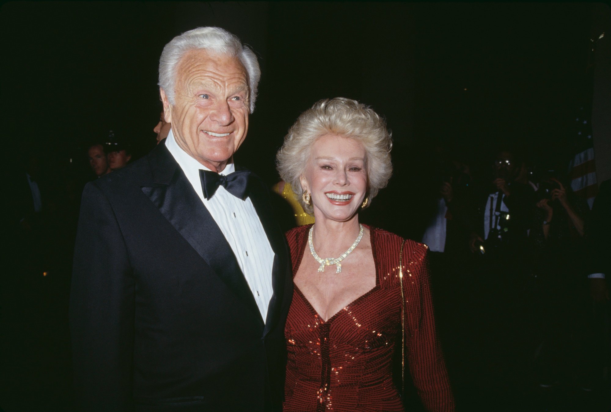 (L-R) Eddie Albert and Eva Gabor smiling in front of a dark background