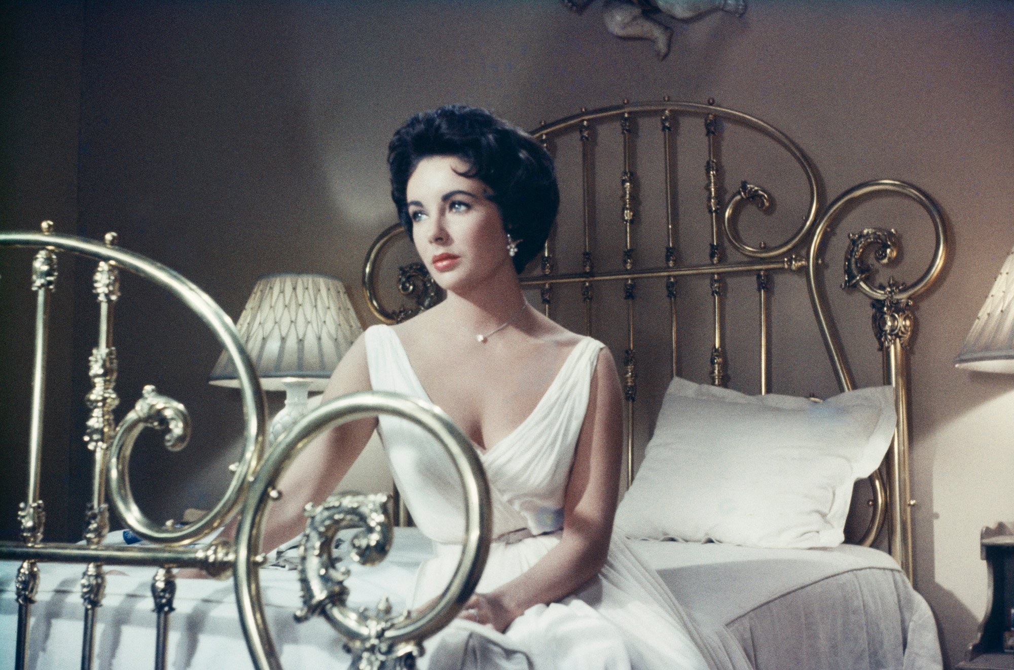 Elizabeth Taylor looking off to the side, seated on a bed, in 'Cat on a Hot Tin Roof'