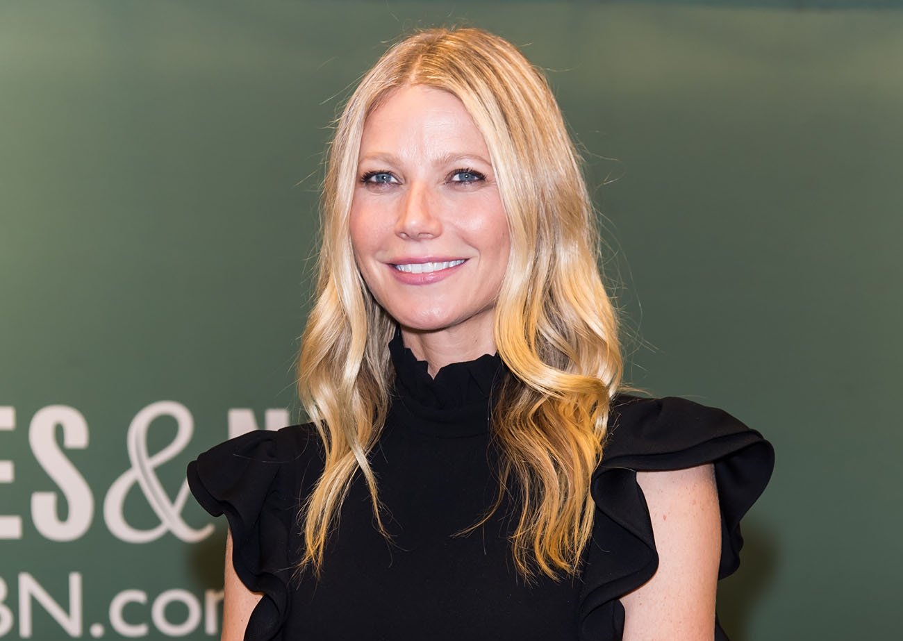 Gwyneth Paltrow smiling in front of green backdrop