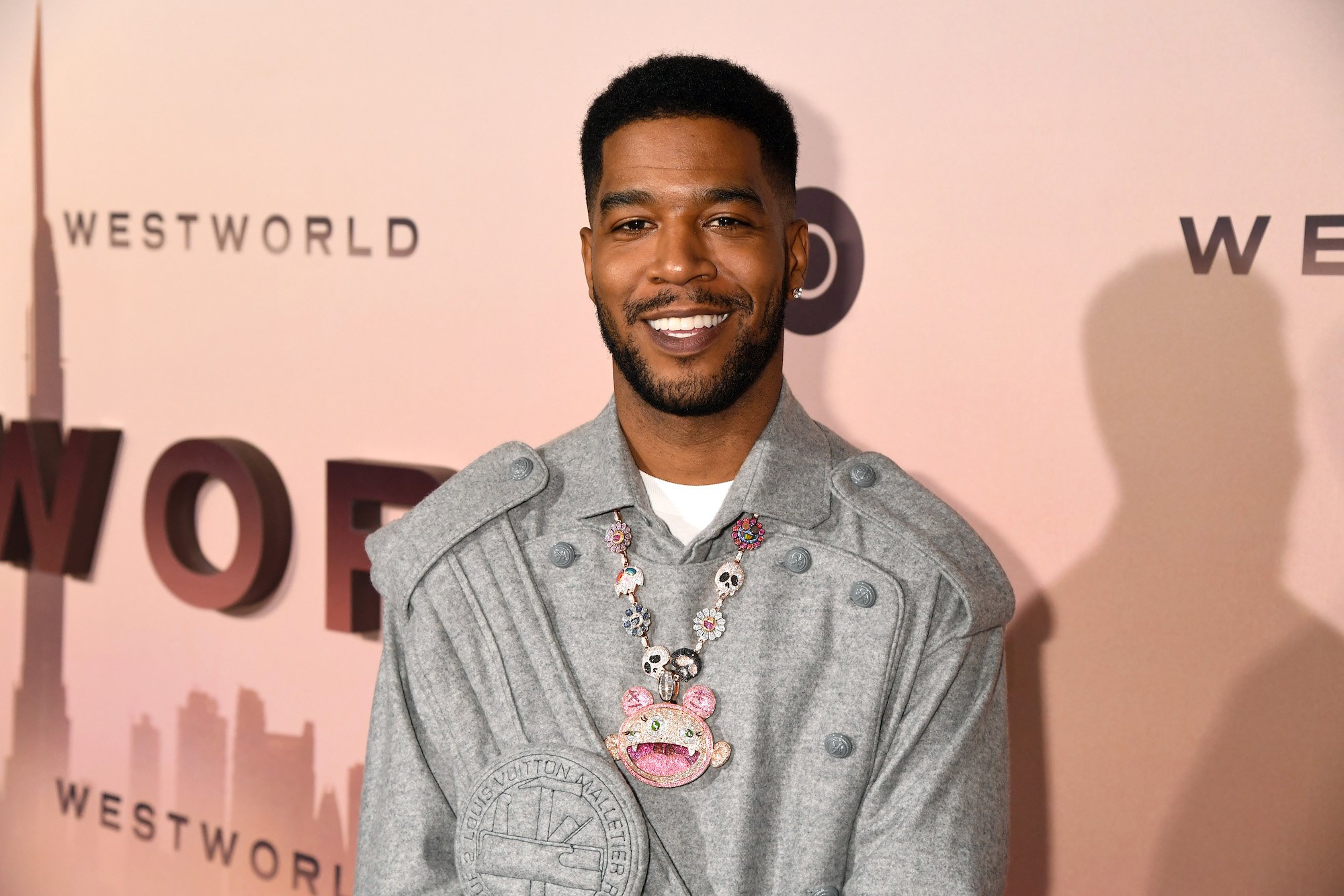 Scott 'Kid Cudi' Mescudi smiling in front of a pink background