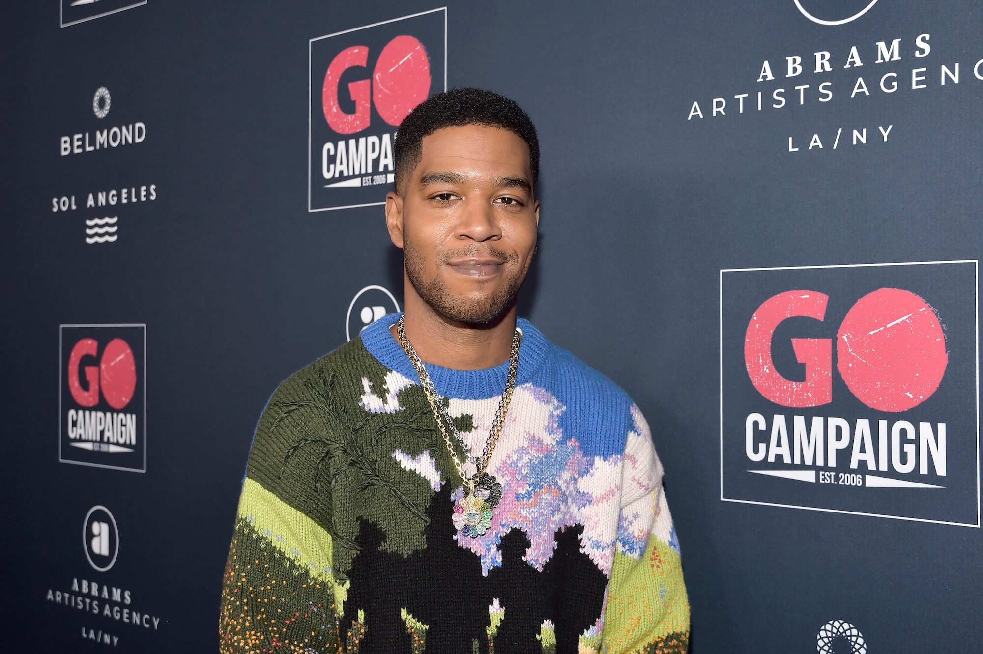 Kid Cudi smiling in front of a black background