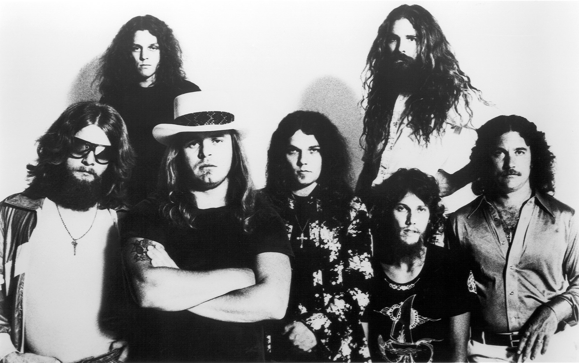 Lynyrd Skynyrd (L-R) Leon Wilkeson, Allen Collins, Gary Rossington, Artimus Pyle (Top), Steve Gaines and Billy Powell looking at the camera not smiling, in black and white
