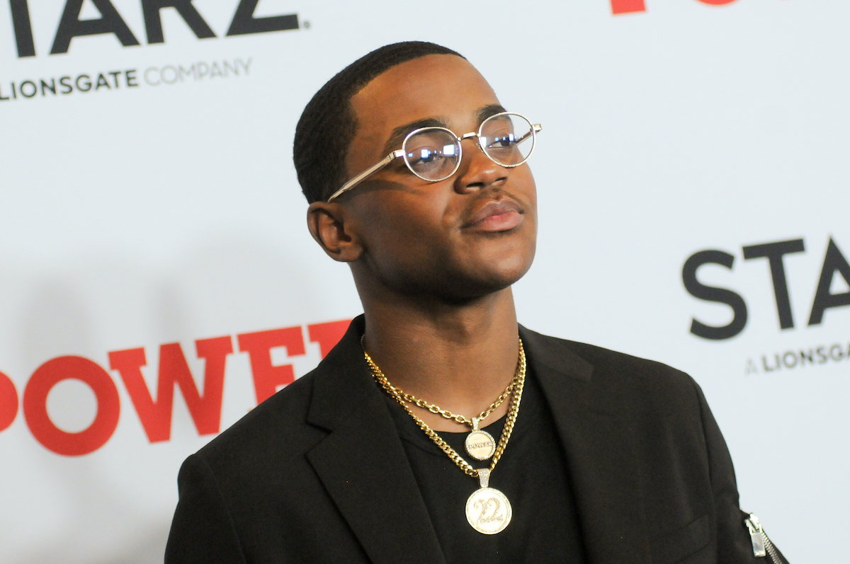 Michael Rainey Jr. on the red carpet wearing a black outfit with gold chains and glasses
