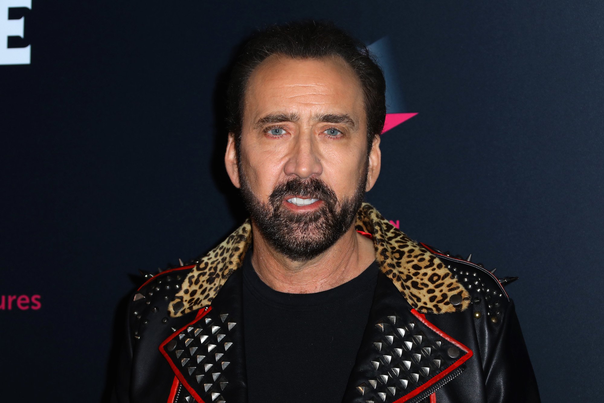 Nicolas Cage standing in front of a black background