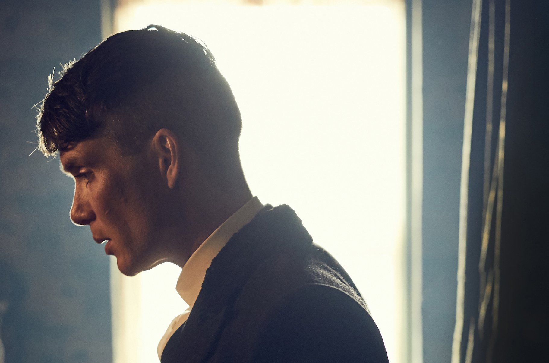 Cillian Murphy, seen in profile with window behind him, as Thomas Shelby in 'Peaky Blinders' 