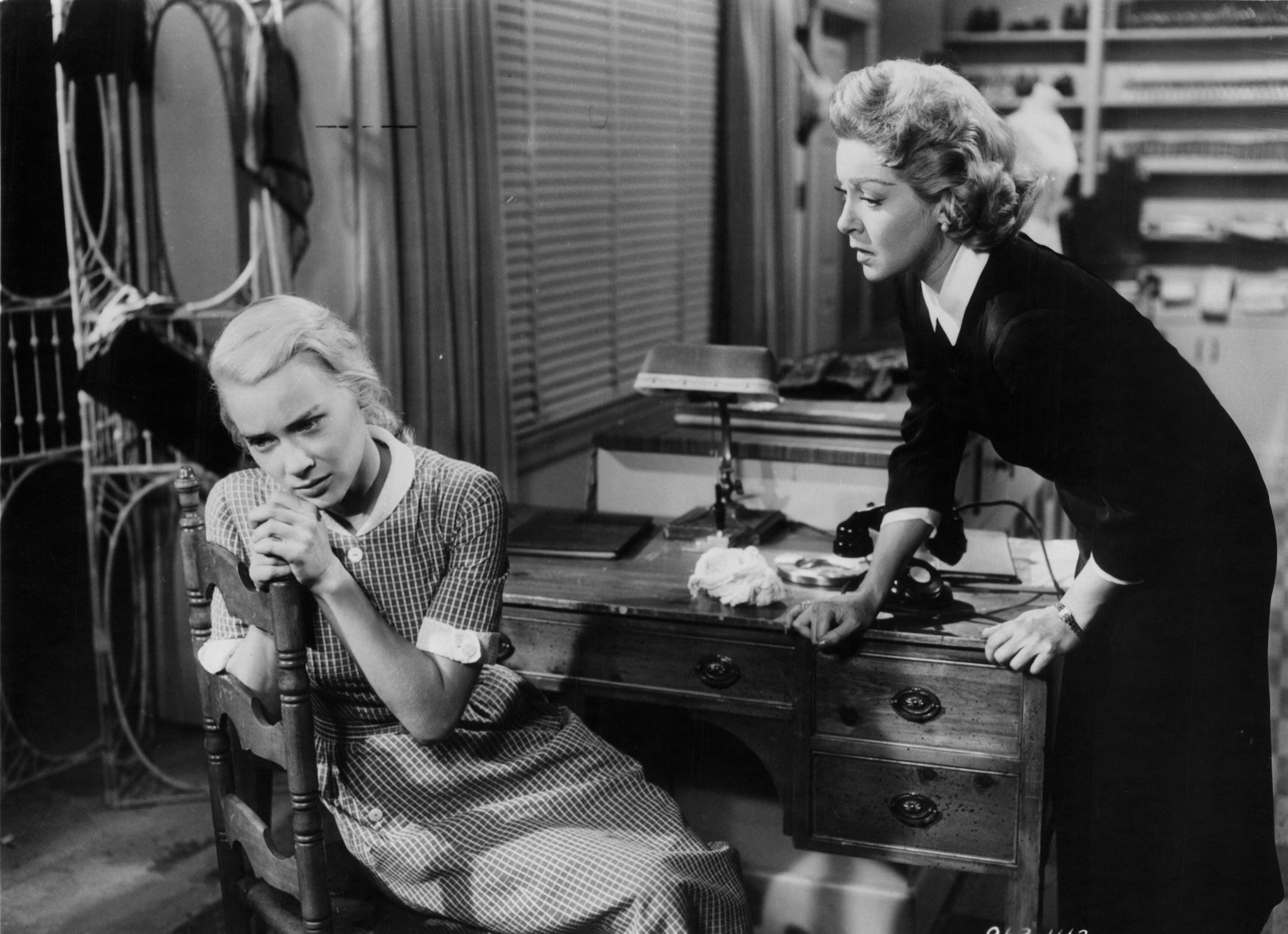 (L-R) Hope Lange sitting on a chair and Lana Turner checking on her in 'Peyton Place' (black and white)