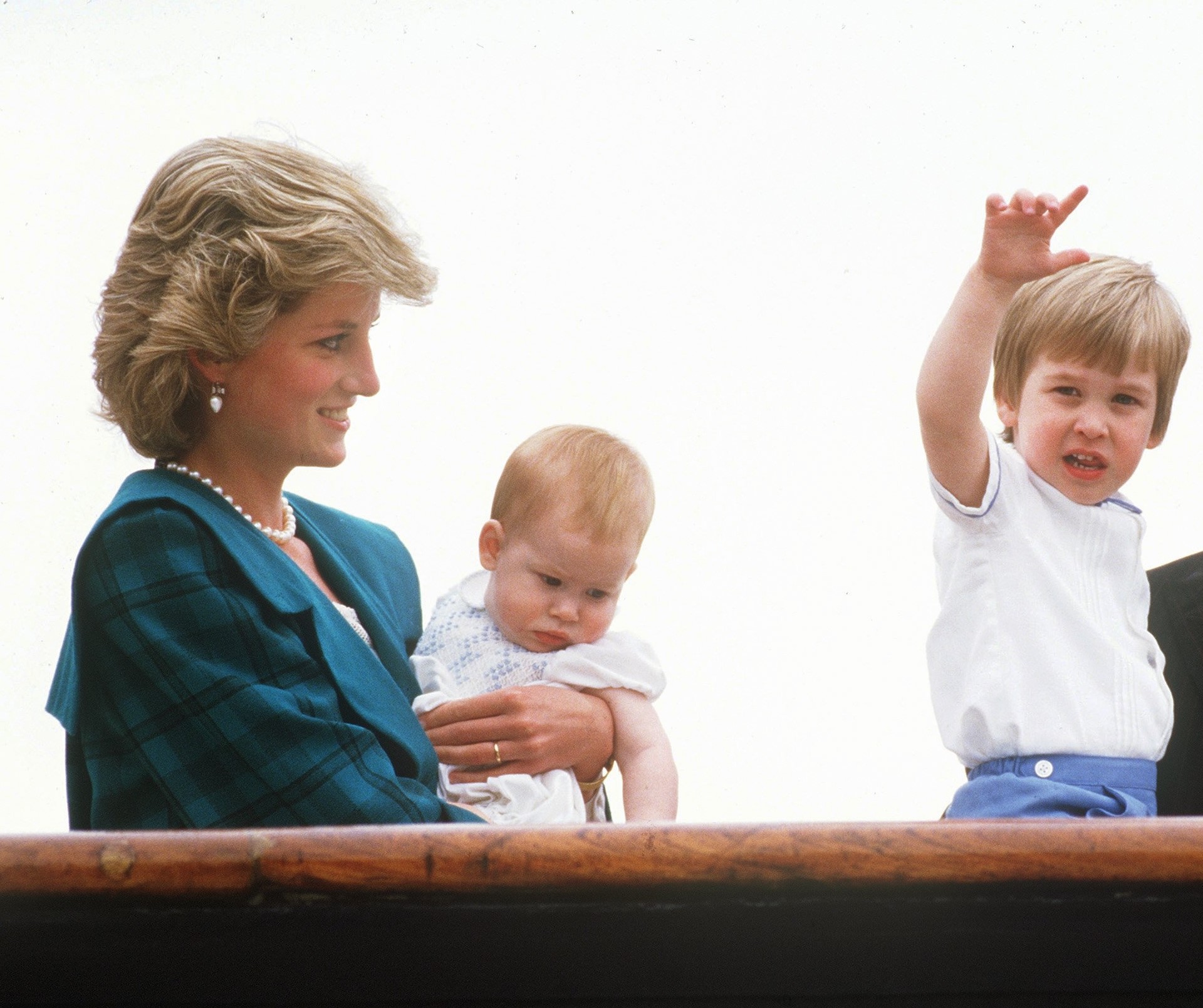Princess Diana holding Prince Harry while looking at Prince William
