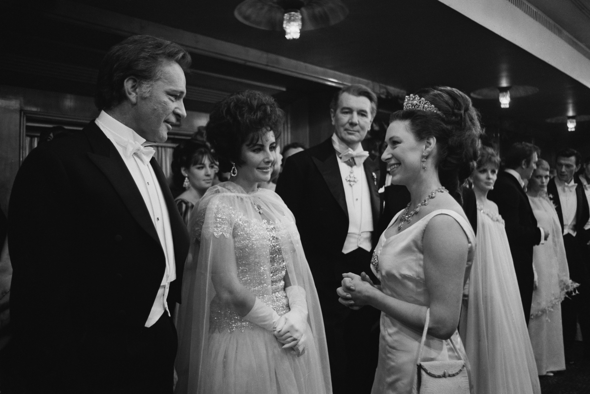 (L-R) Richard Burton, Elizabeth Taylor, and Princess Margaret talking, in black and white