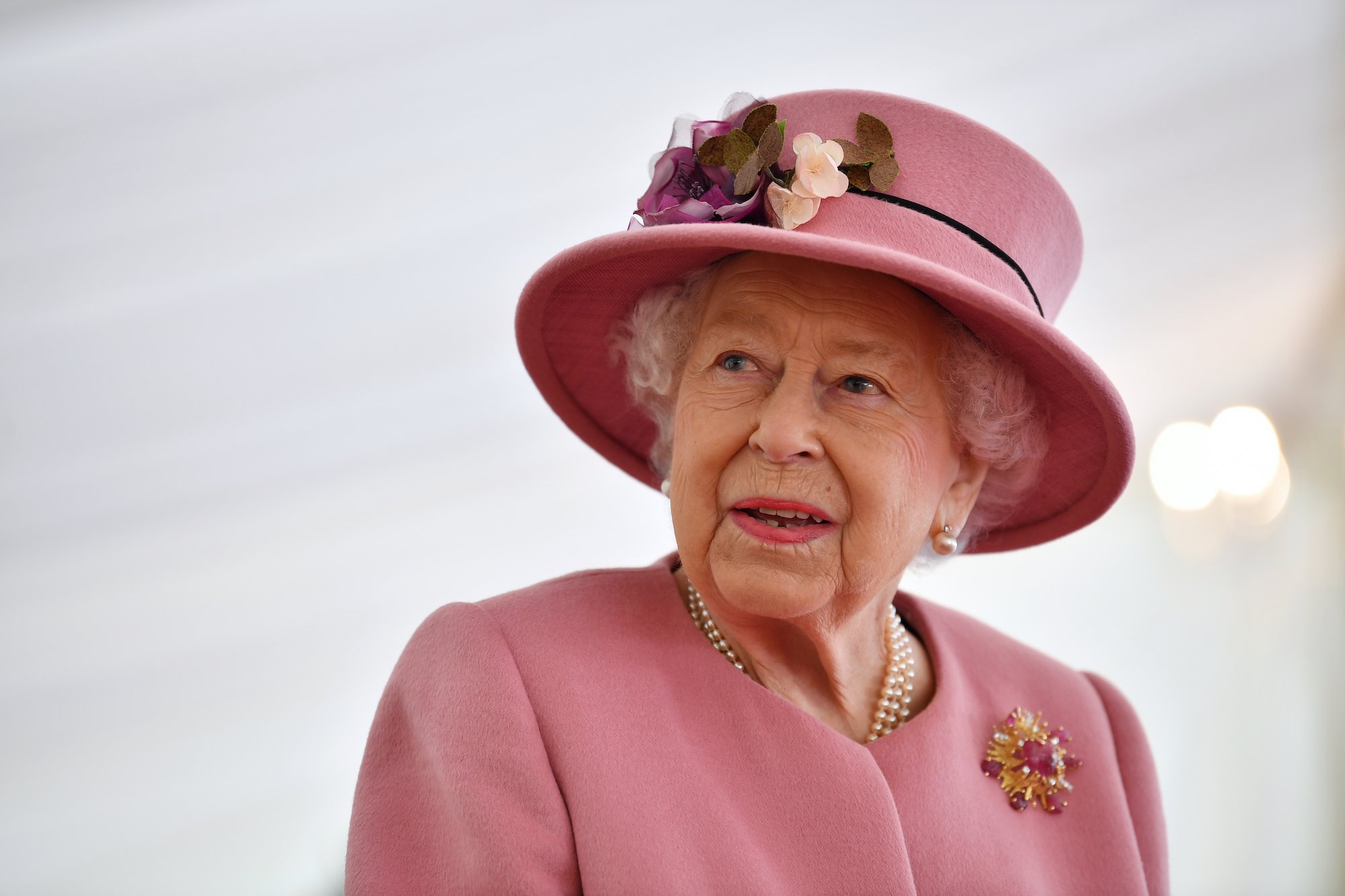 Queen Elizabeth II smiling in a pink hat