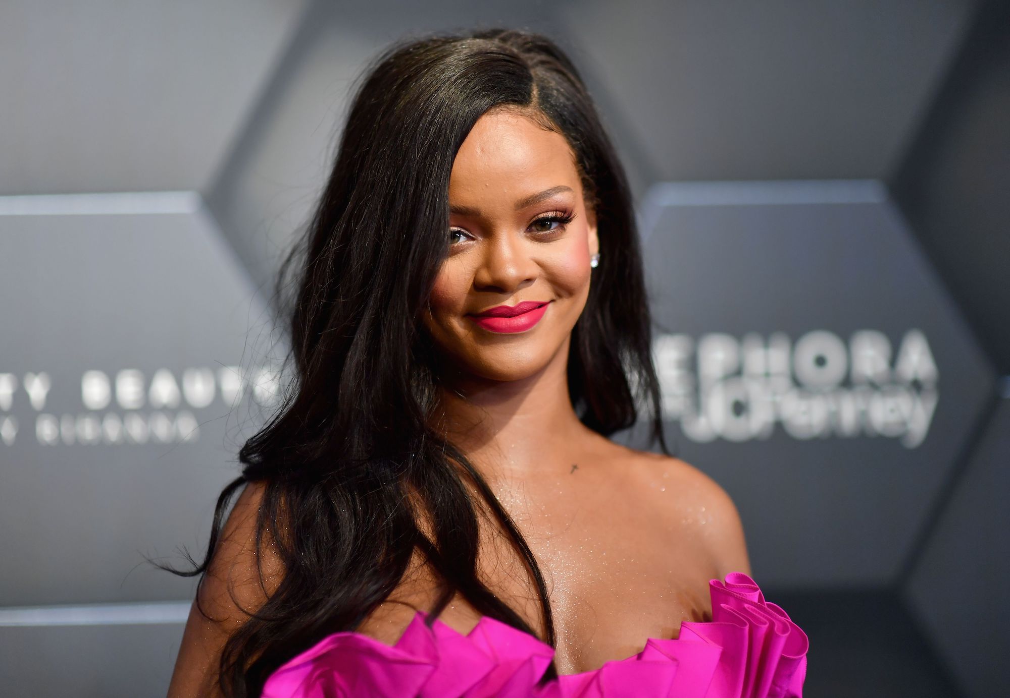 Rihanna smiling in front of a blurred black background