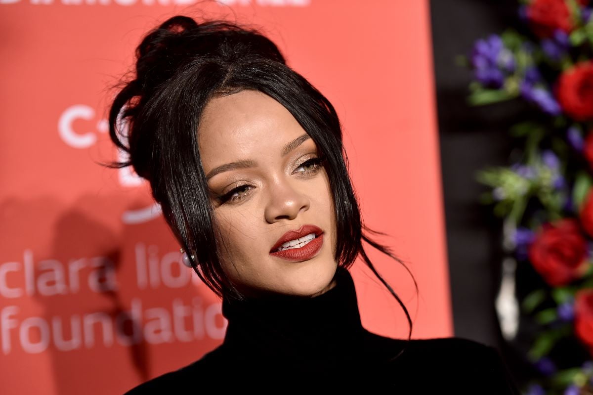 Rihanna headshot with the singer wearing a black turtleneck, red lipstick, and her hair in a bun.