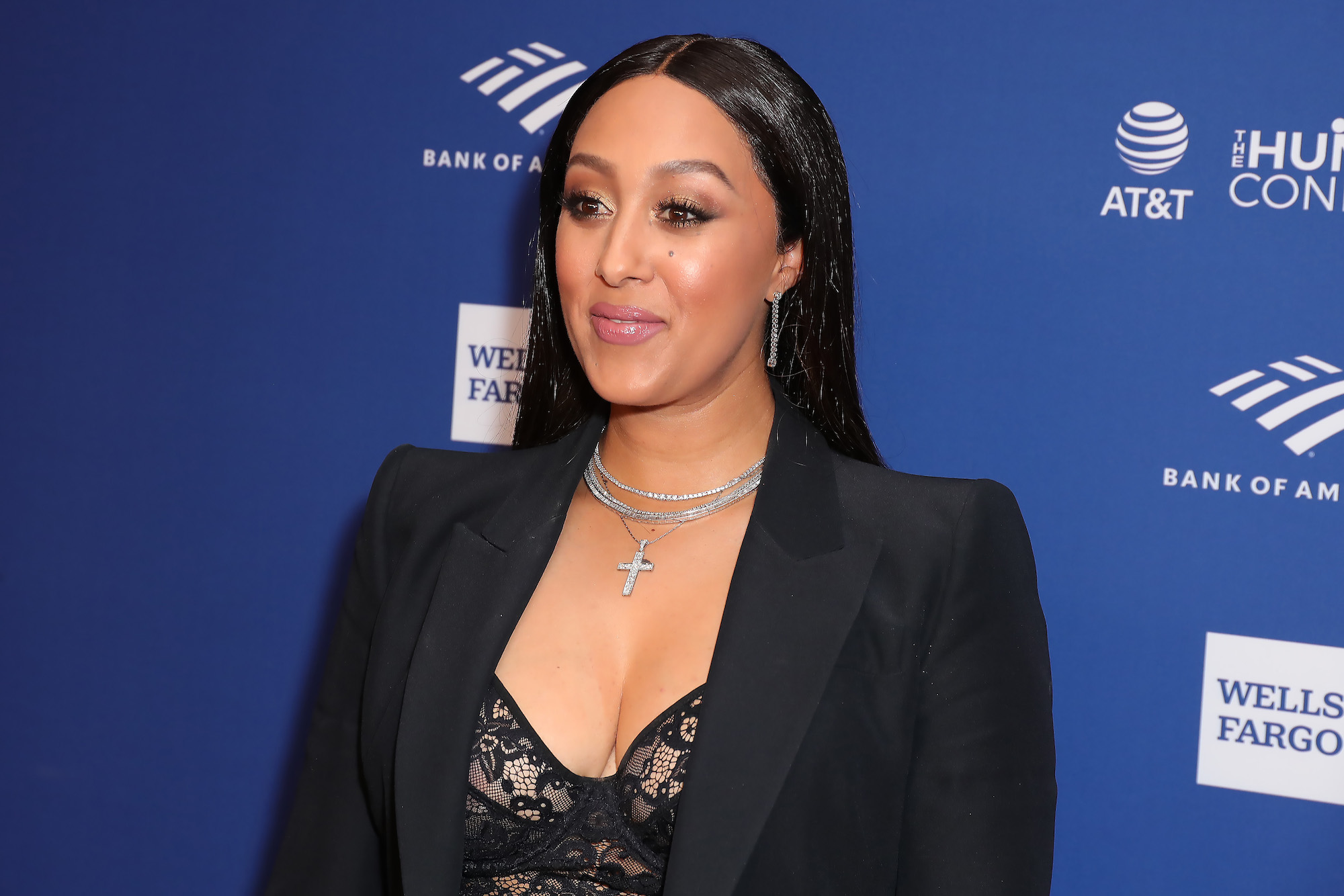 Tamera Mowry-Housley smiling in front of a blue background