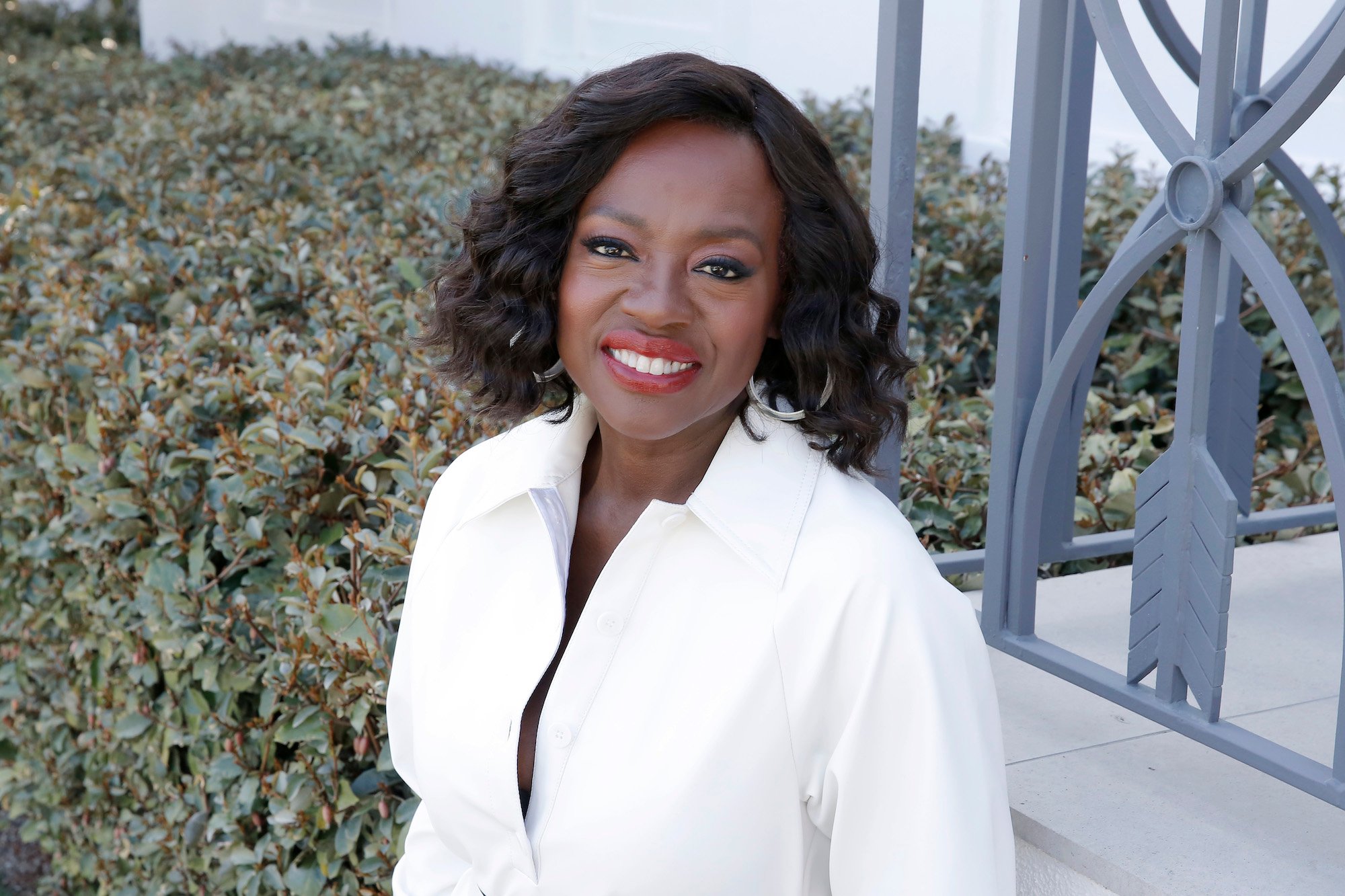 Viola Davis smiling in front of hedges