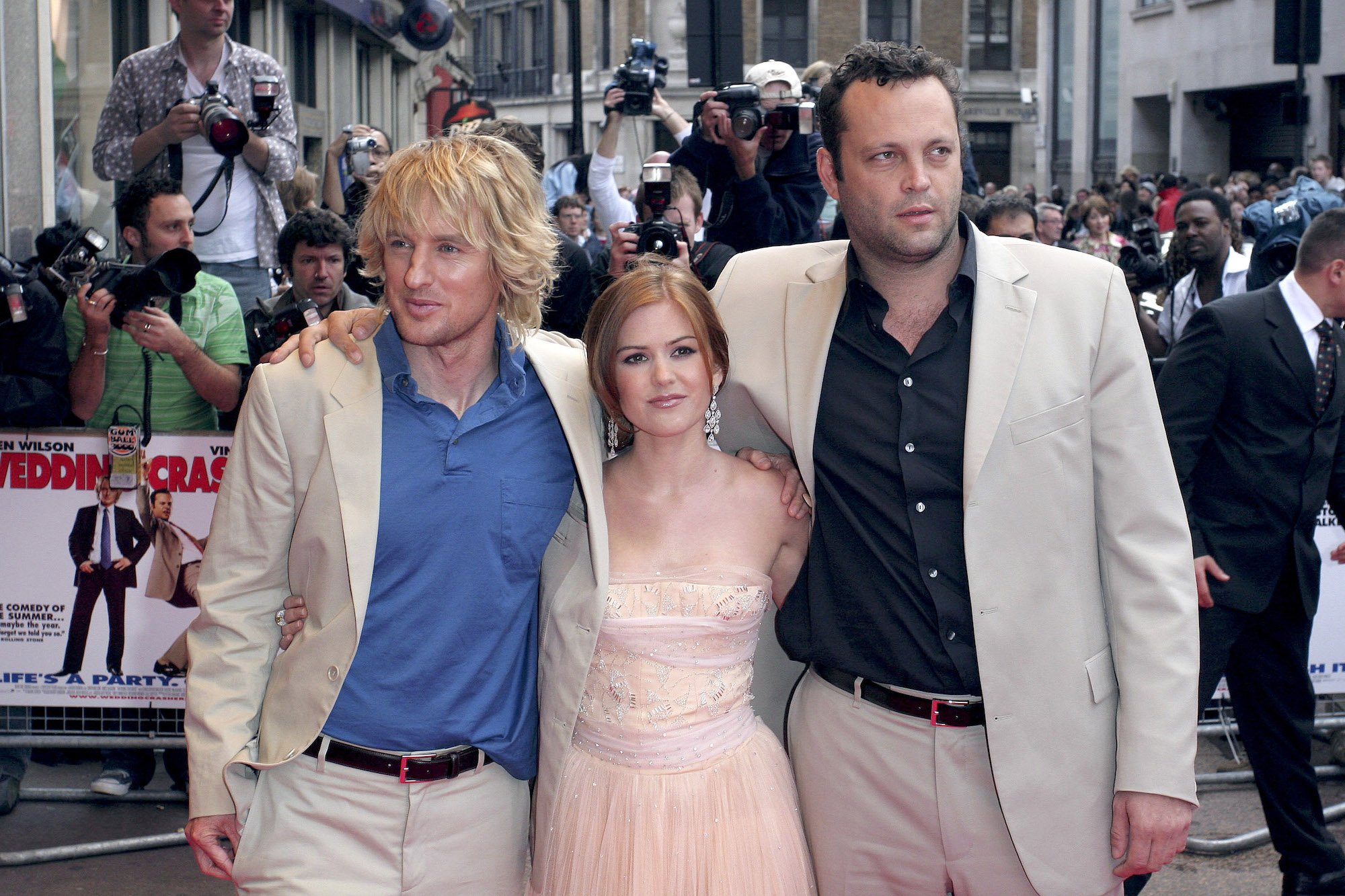(L-R) Owen Wilson, Isla Fisher, and Vince Vaughn smiling in front of a crowd