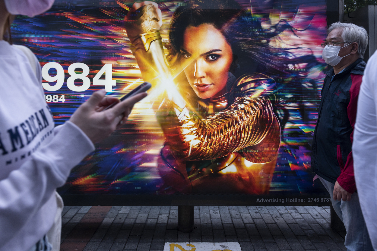 A person walks past an advertisement for 'Wonder Woman 1984'
