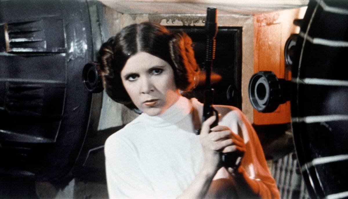 Carrie Fisher as Princess Leia holding gun