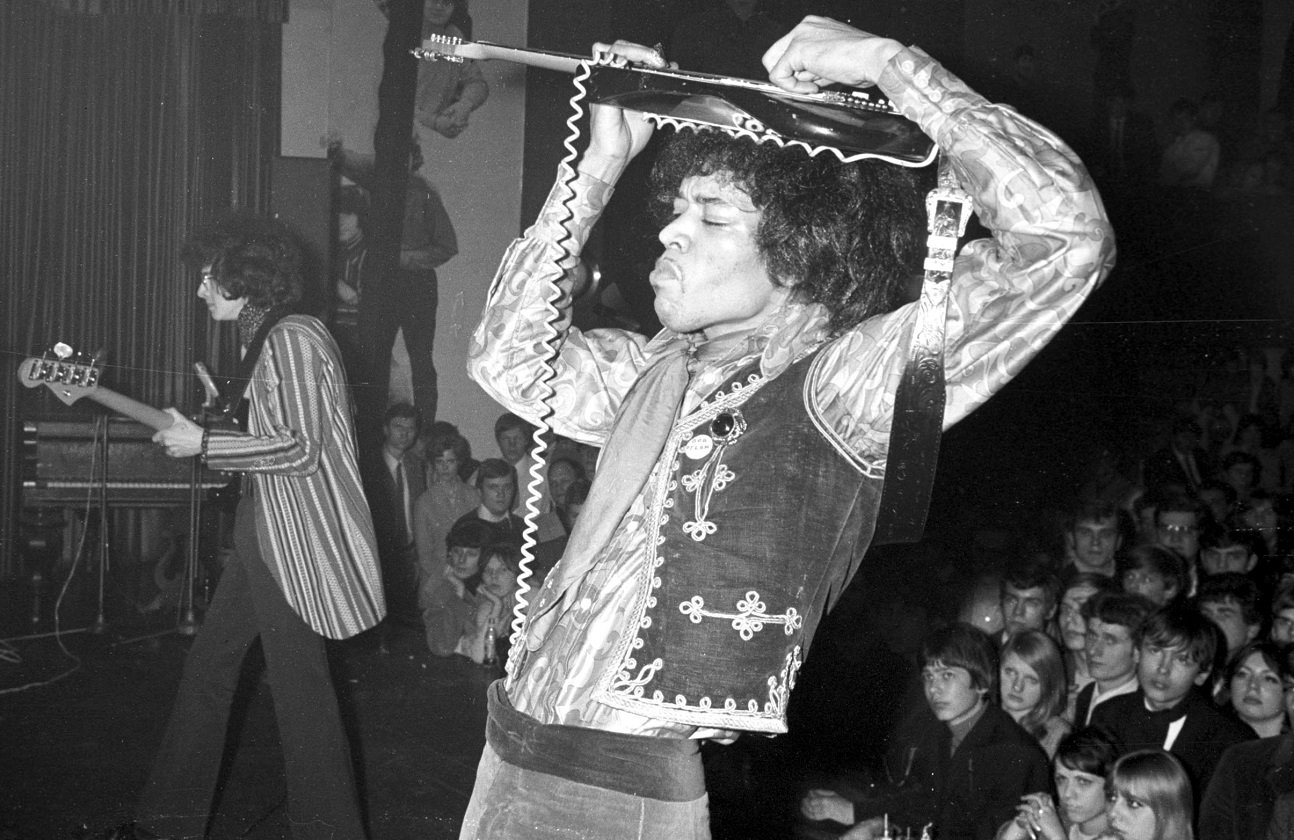 Hendrix playing guitar on top of his head