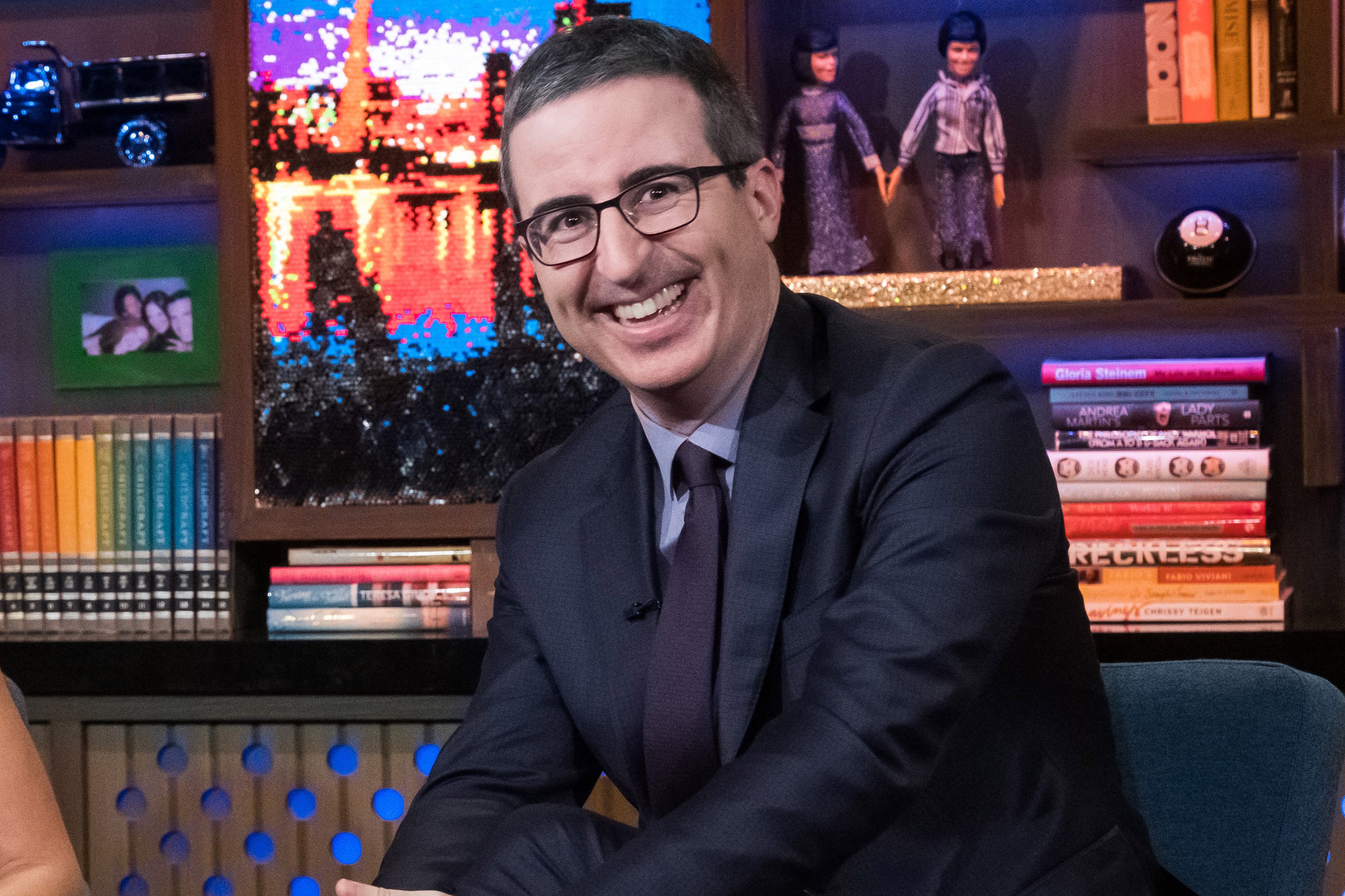 John Oliver in front of dolls