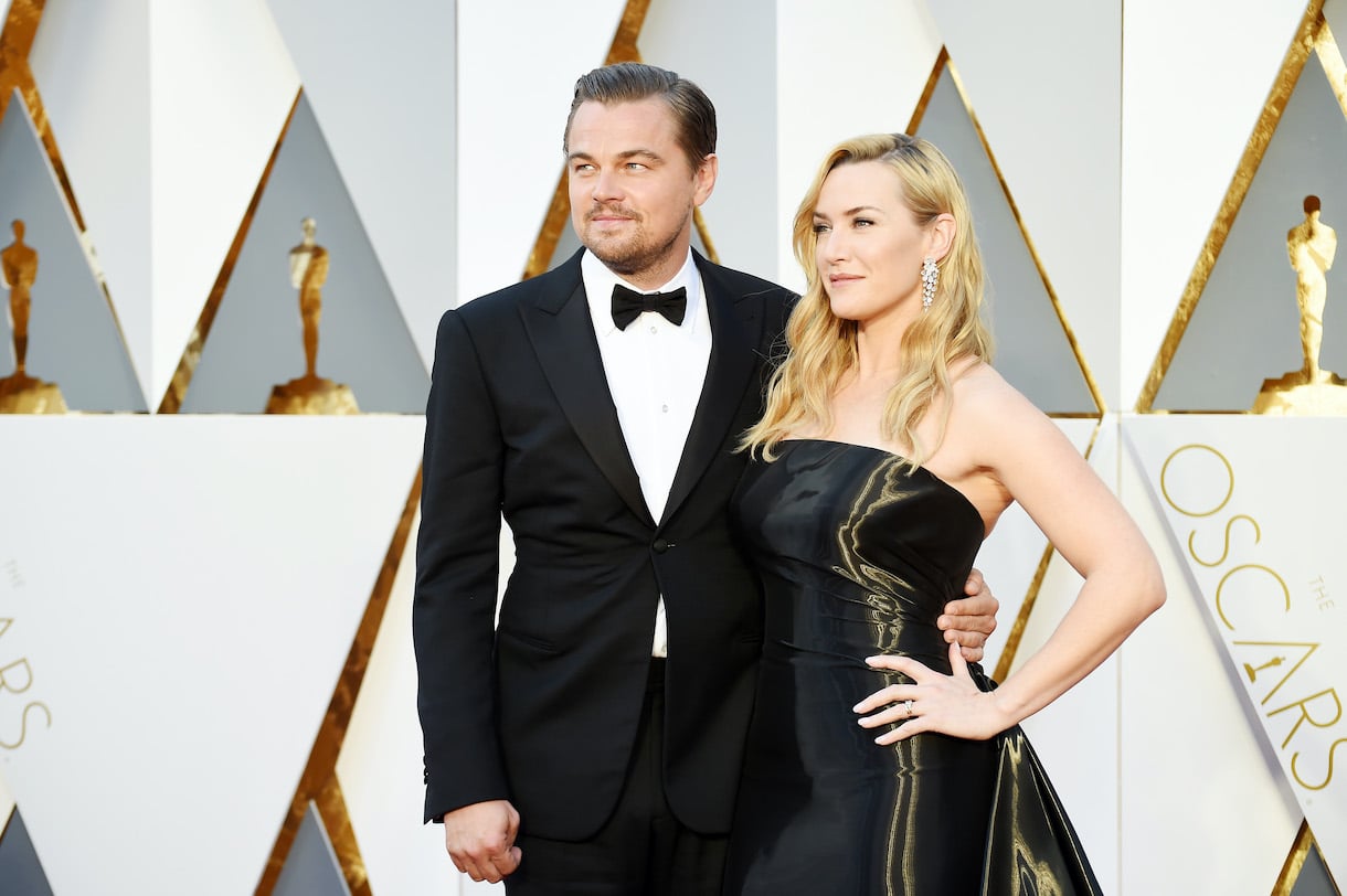 Leonardo DiCaprio and Kate Winslet posing in a suit and black gown respectively at the Oscars