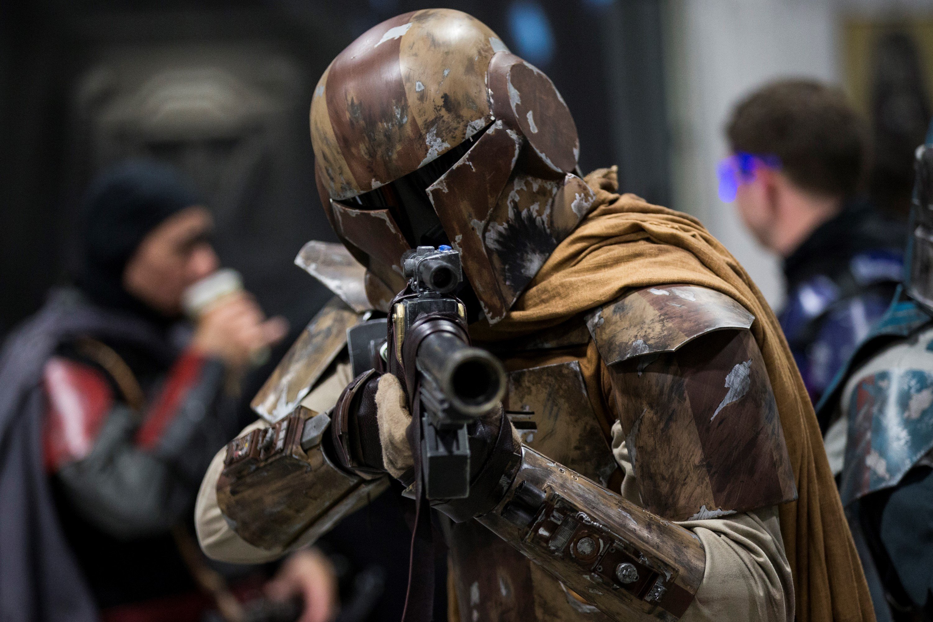 A Star Wars/Mandalorian cosplayer holding a blaster
