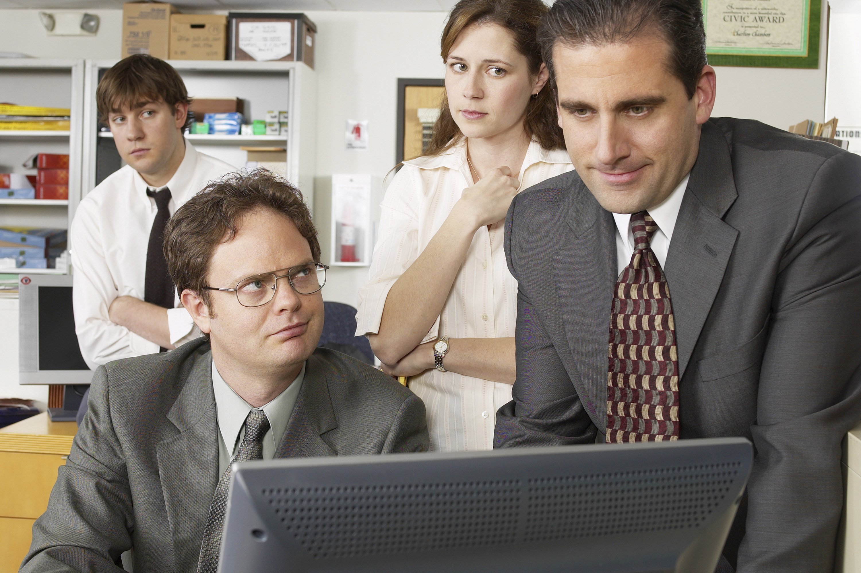 John Krasinski, Rainn Wilson, Jenna Fischer, and Steve Carell around a computer